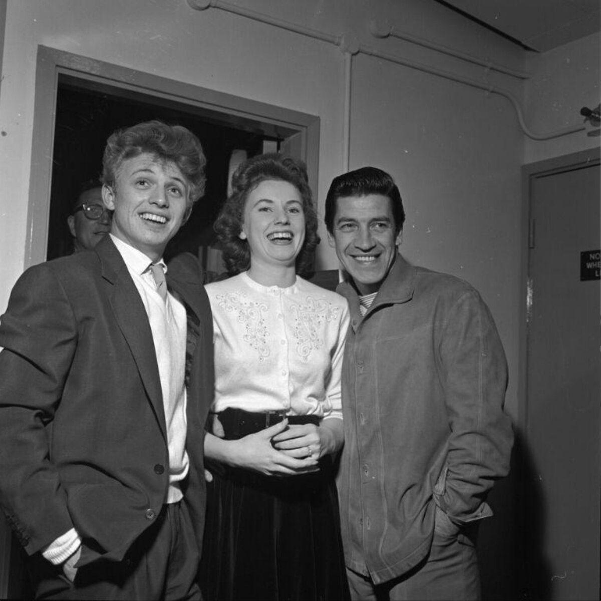 Three Smiling Celebrities Posing Backstage