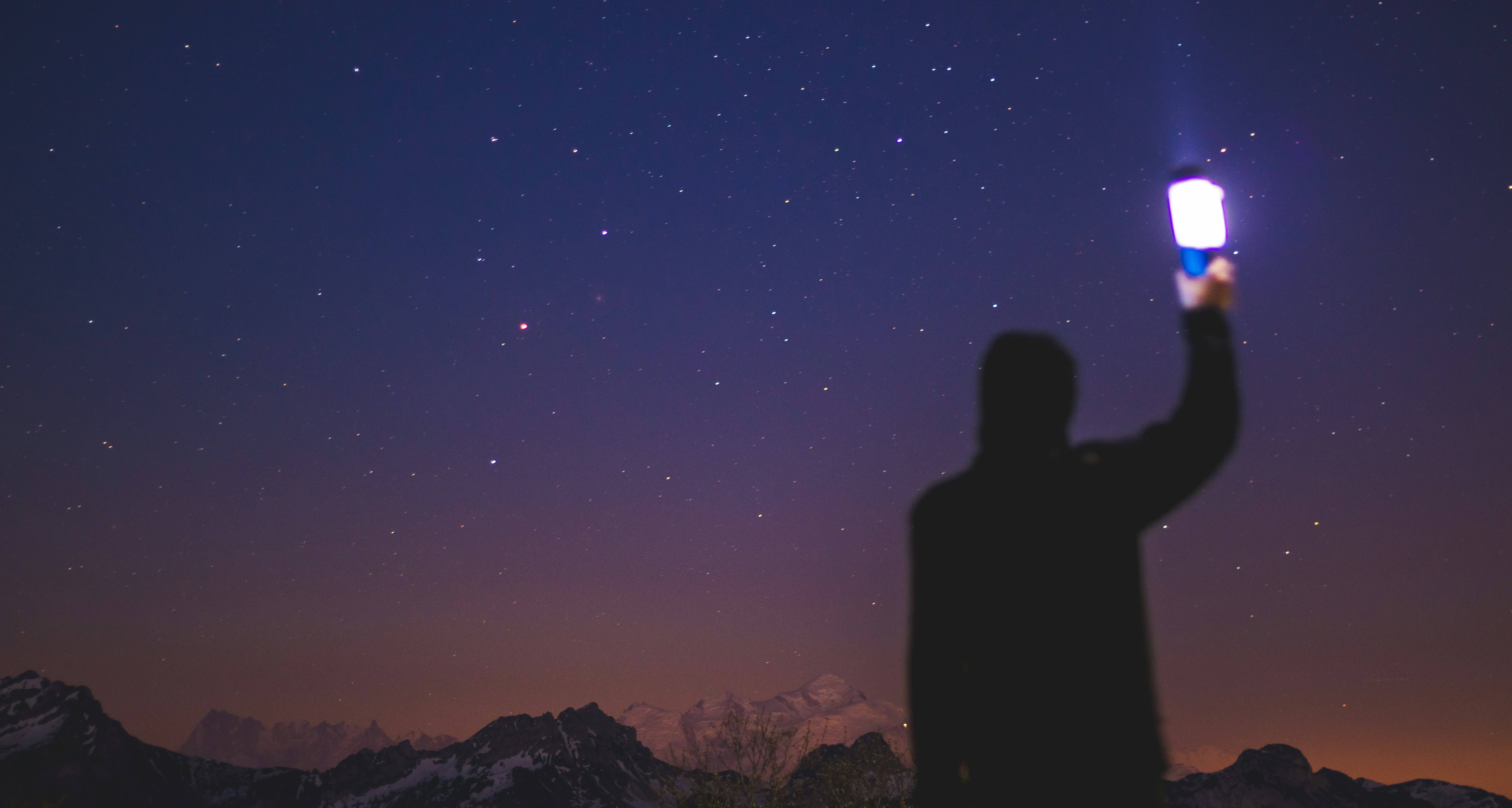 Person Holding Flashlight Under Starry Sky