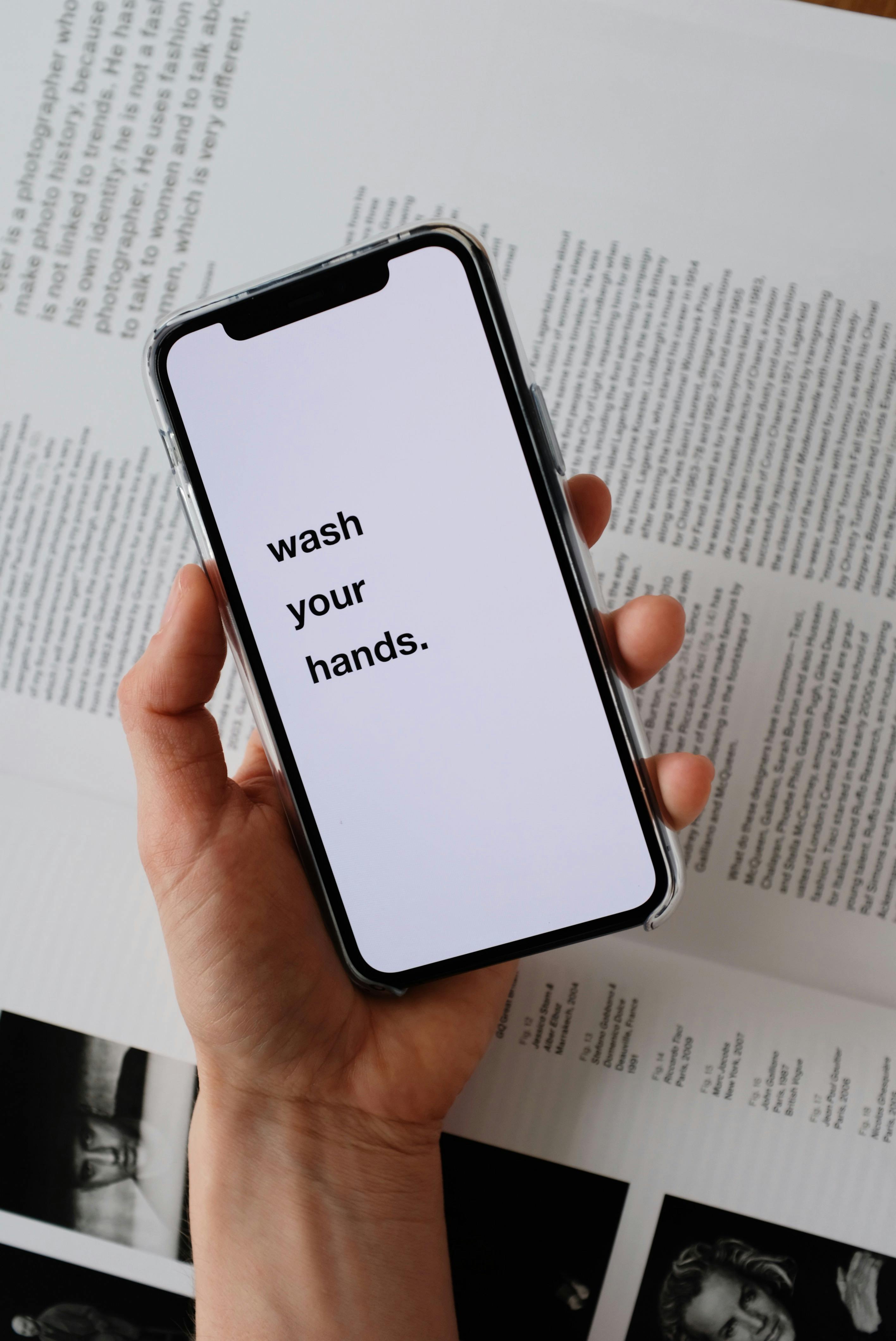 Hand Holding Phone With Wash Your Hands Text