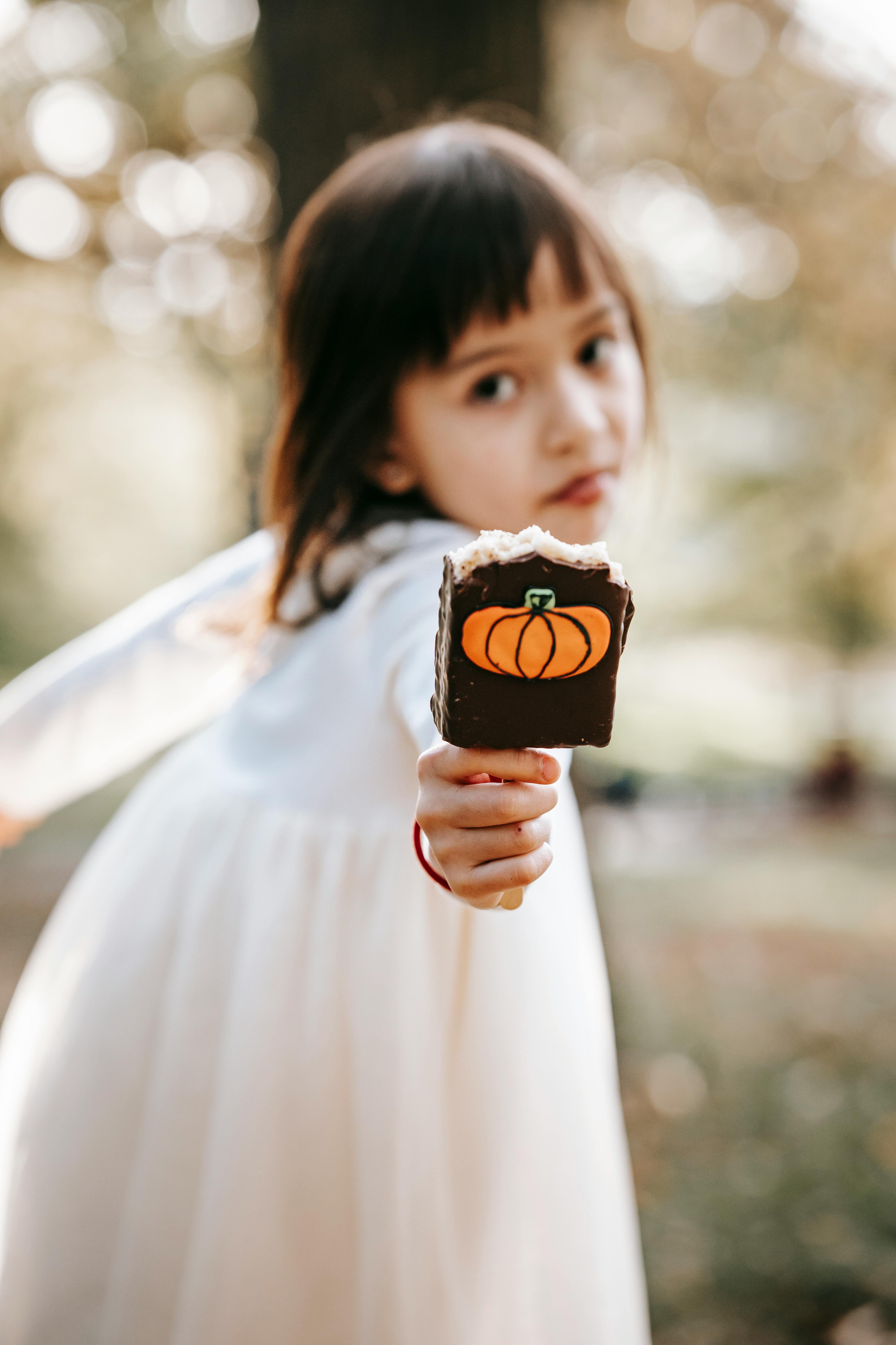 Girl holding pumpkin decorated ice cream bar