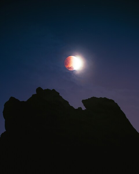 Partial Blood Moon Over Mountain Peaks
