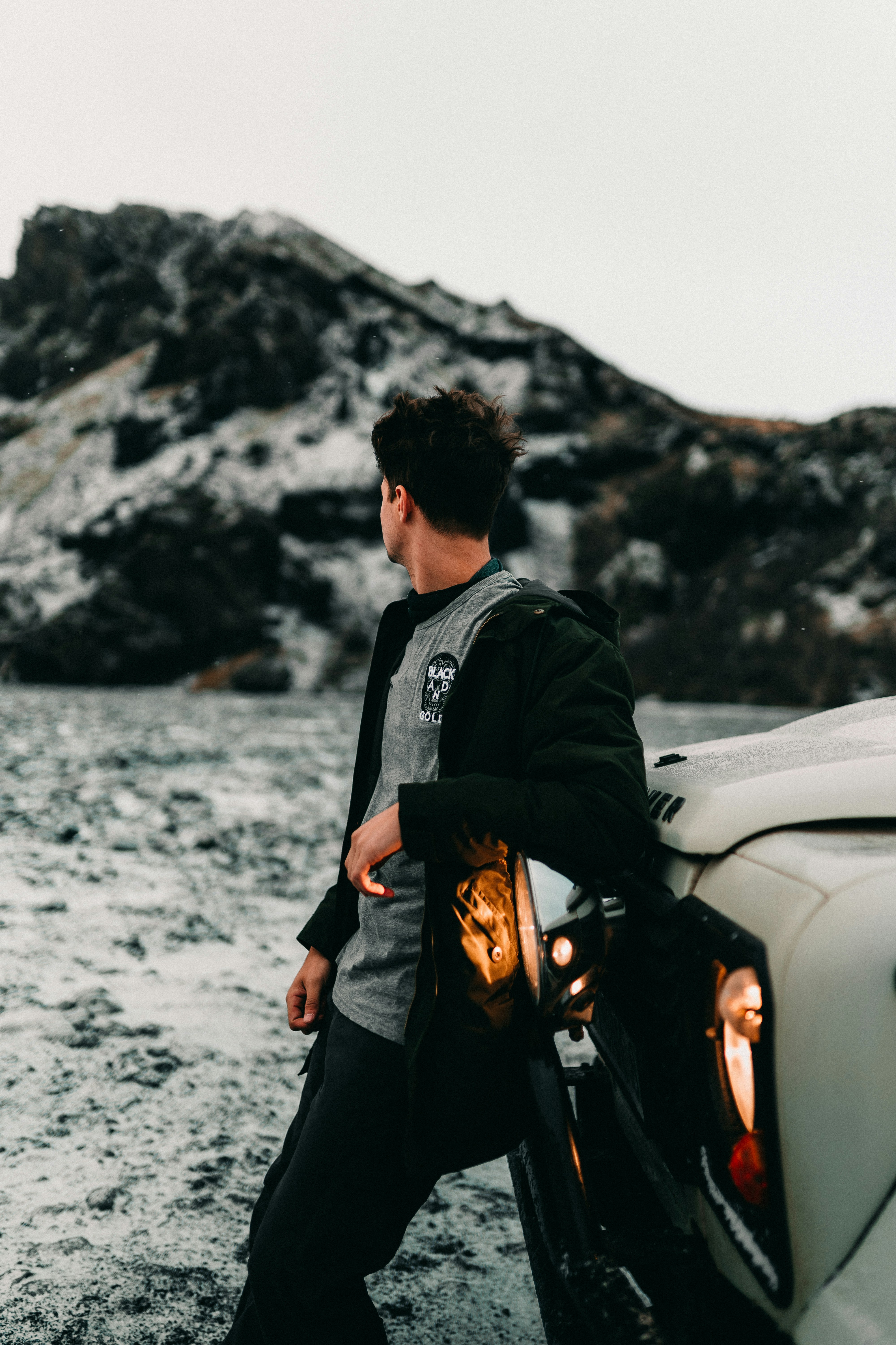 Man Leaning On Car By Snowy Mountain