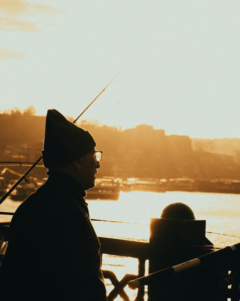 Fisherman Fishing at Sunset by River