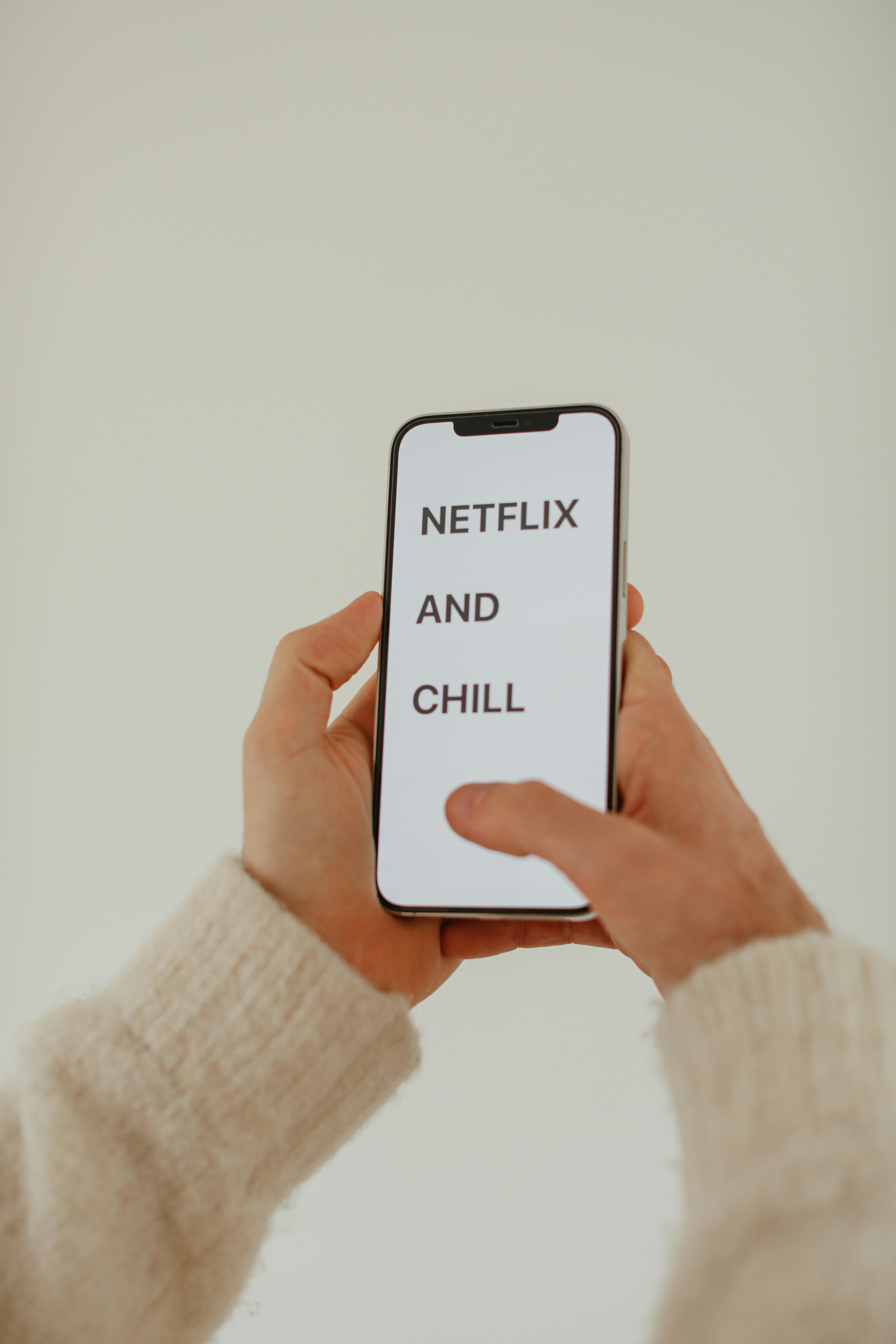 Hands Holding Phone With Netflix And Chill Text