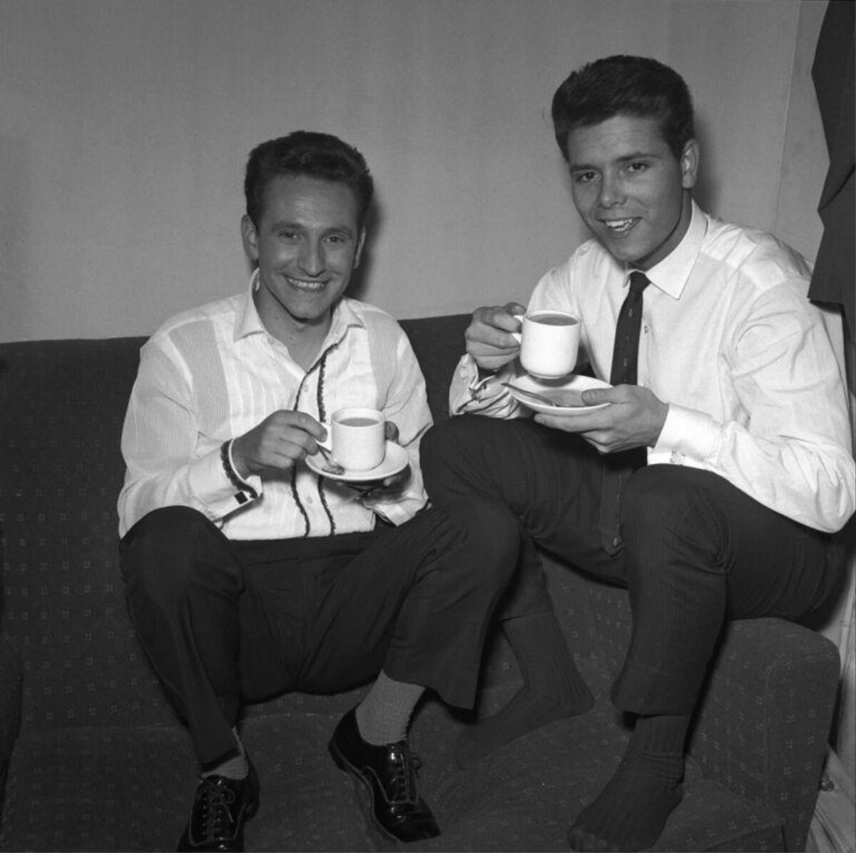 Two Men Drinking Coffee On Sofa
