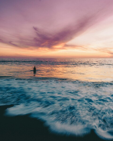 Lone Figure in Sea at Sunset