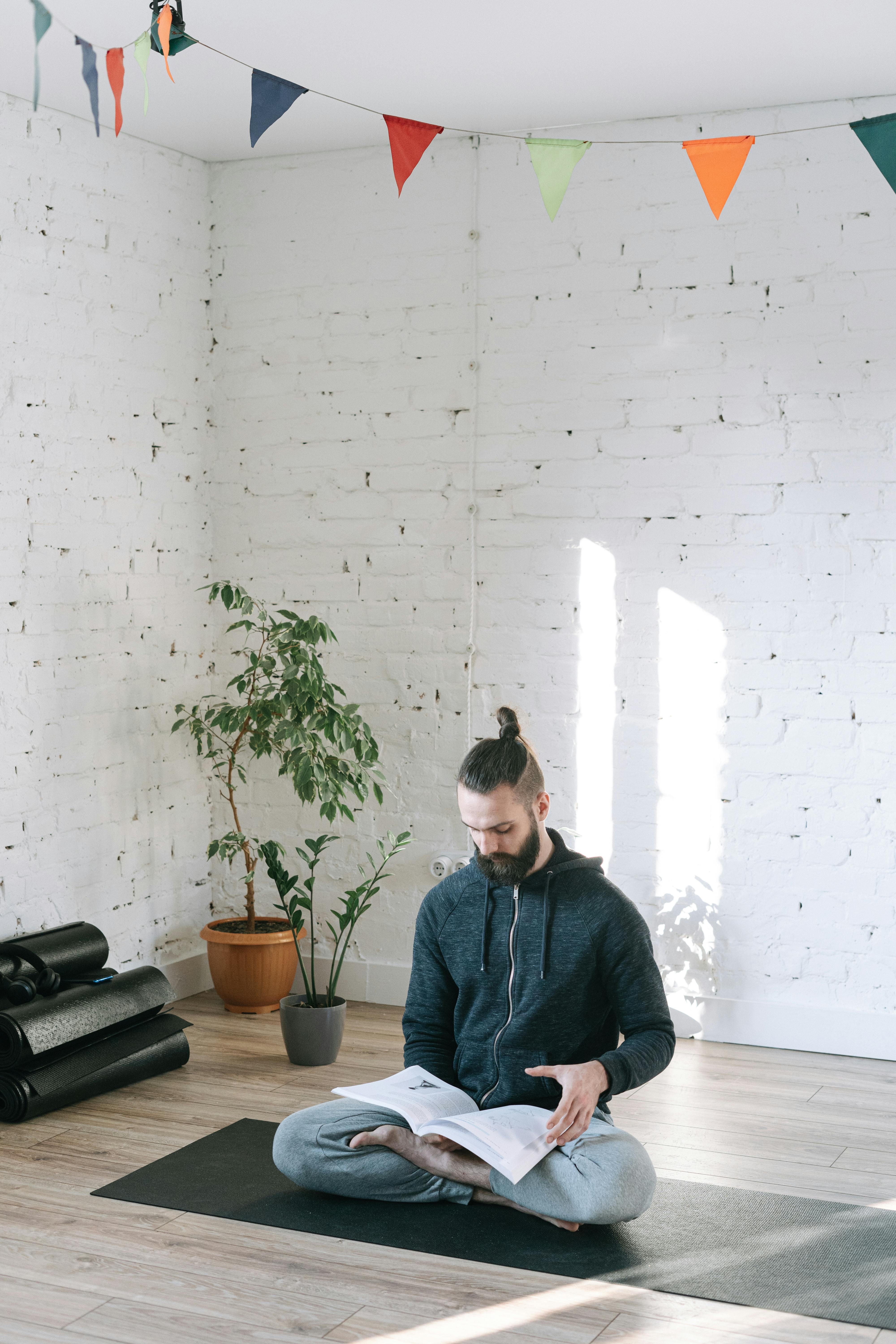 Man Reading While Sitting on Yoga Mat