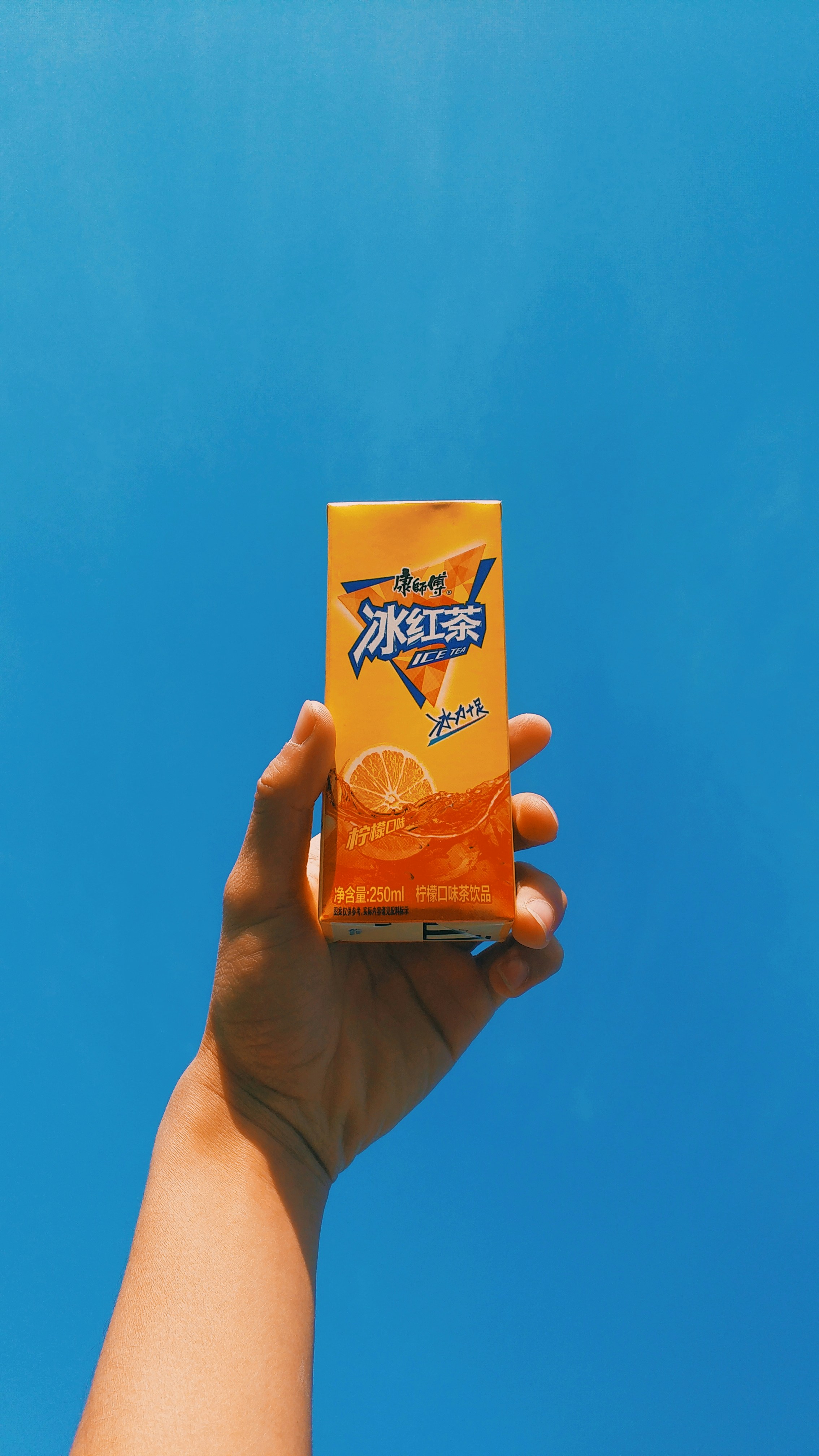 Hand Holding Ice Tea Against Blue Sky