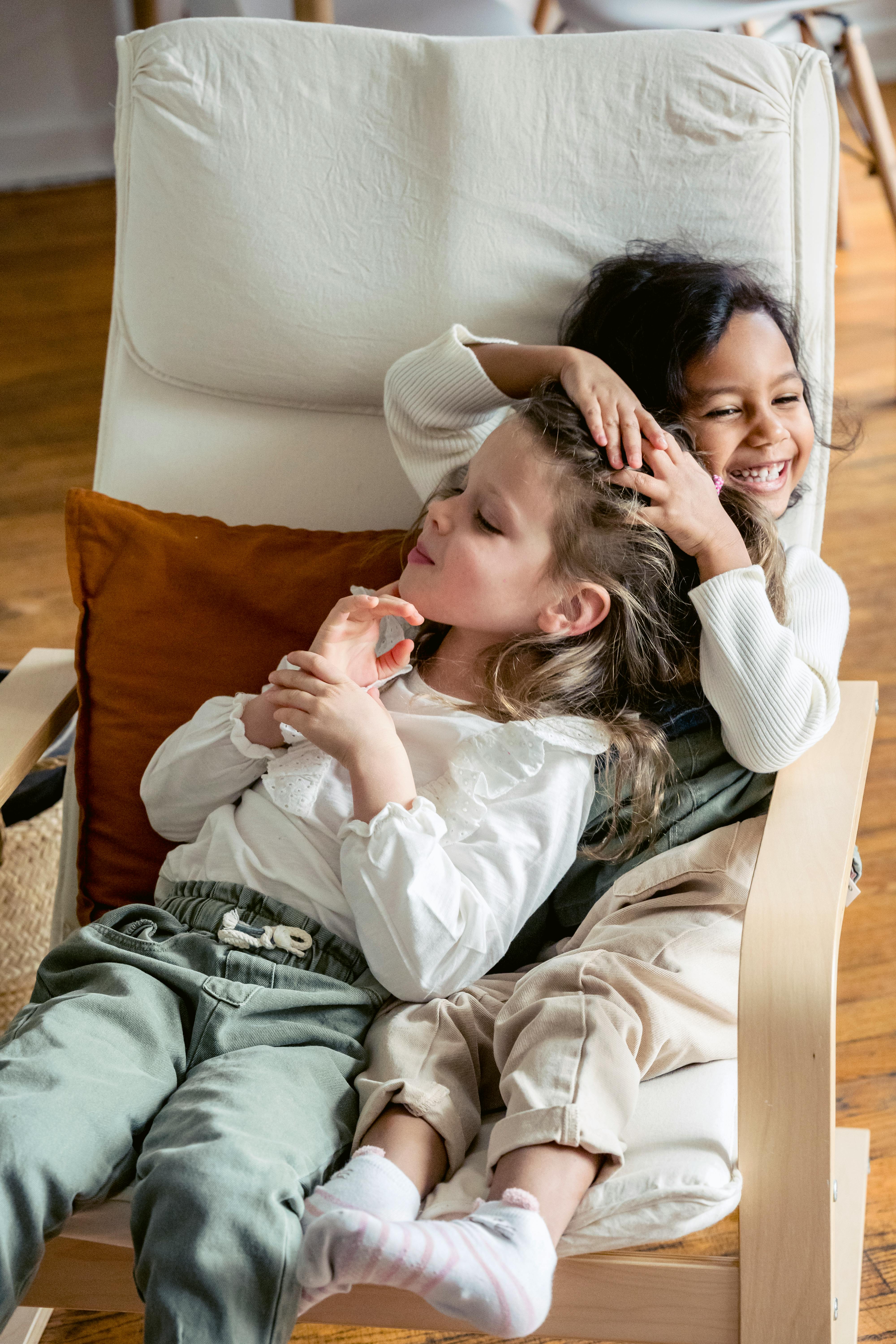 Two Girls Playfully Cuddling in Armchair