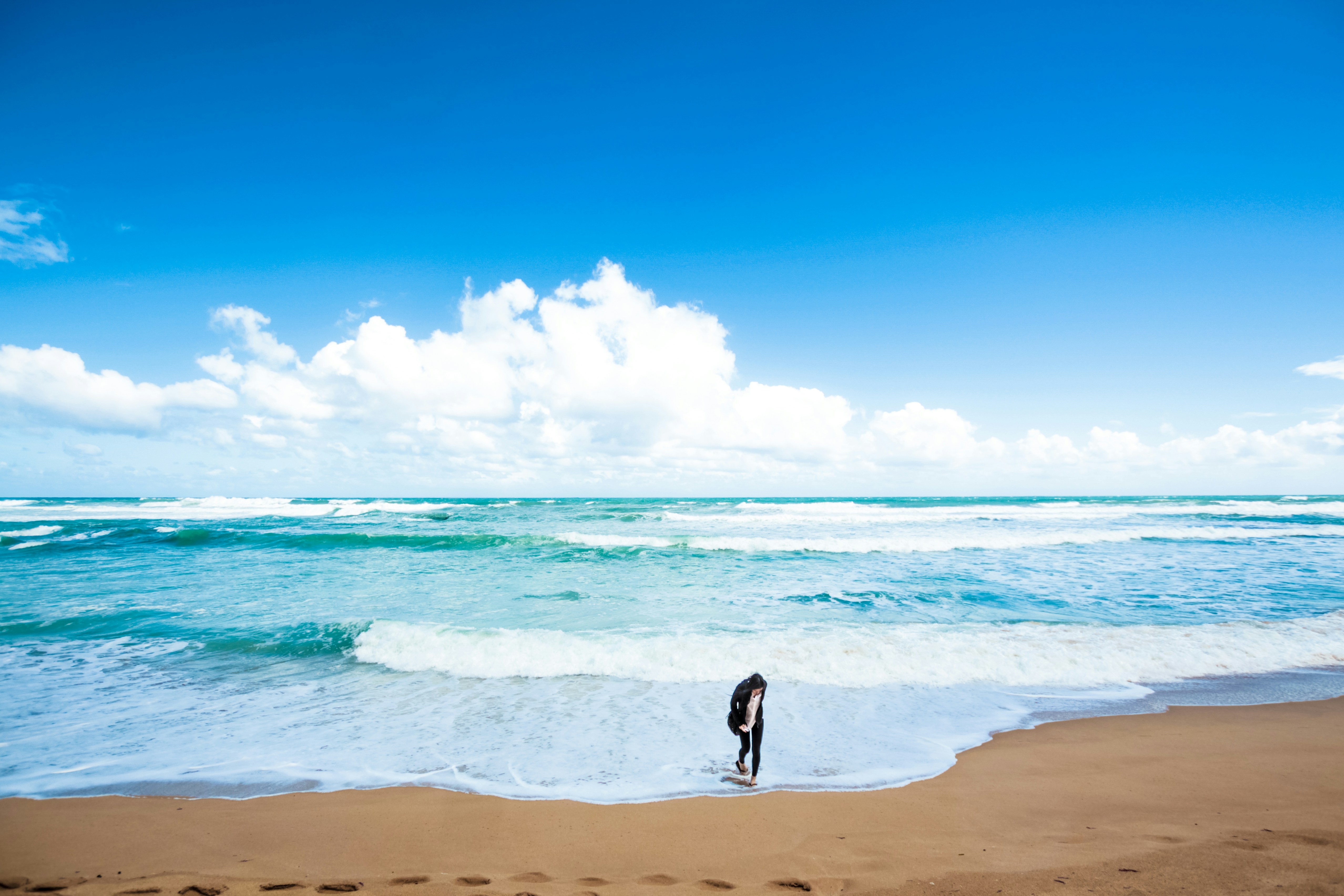 Person Walking on Sunny Seaside Beach