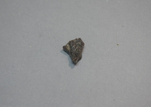 Small Dark Rock Fragment on Gray Background