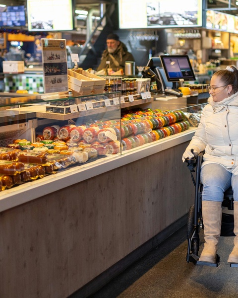 Woman in wheelchair at market cheese counter