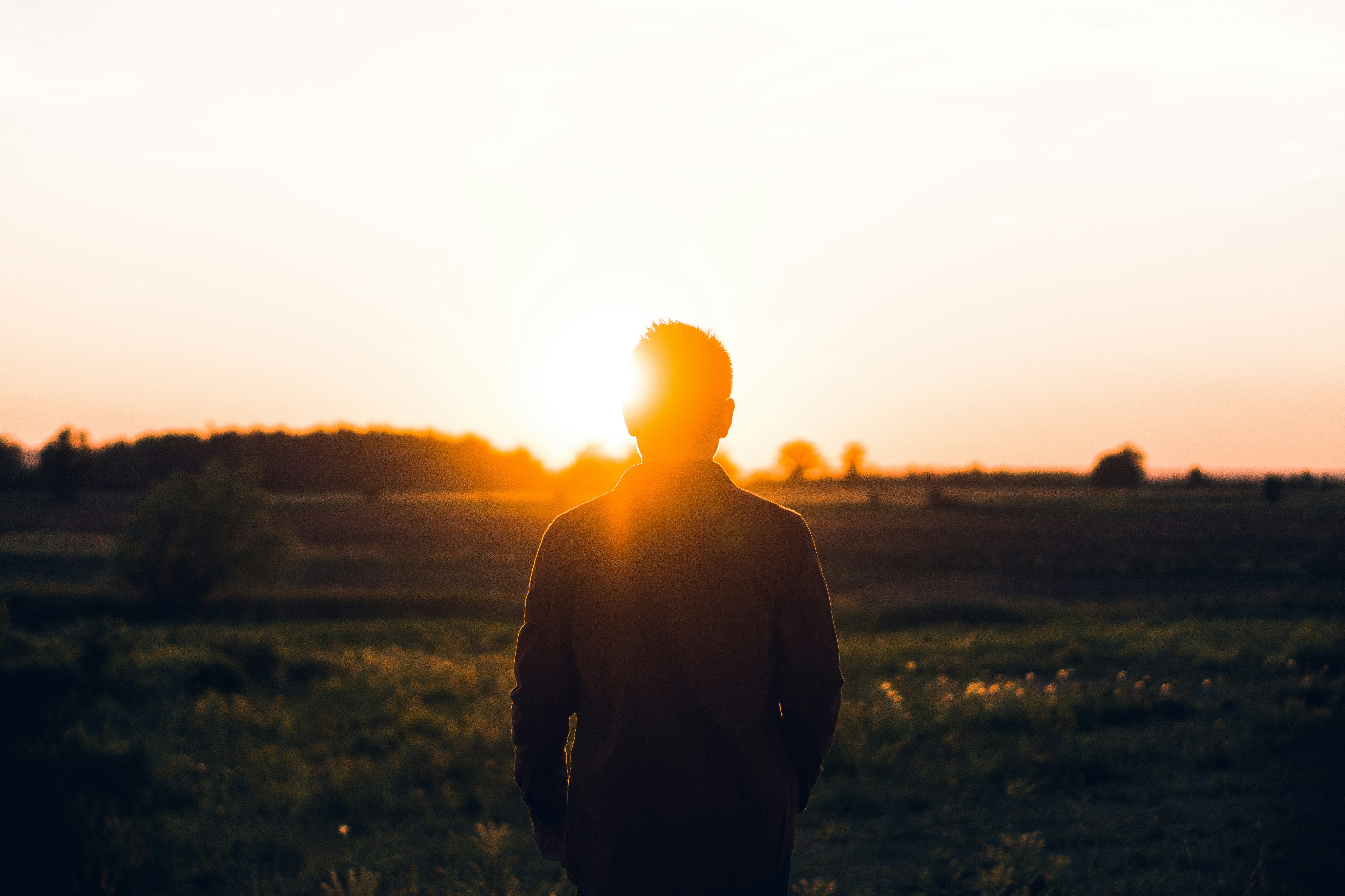 Man Facing Sunset on Open Field