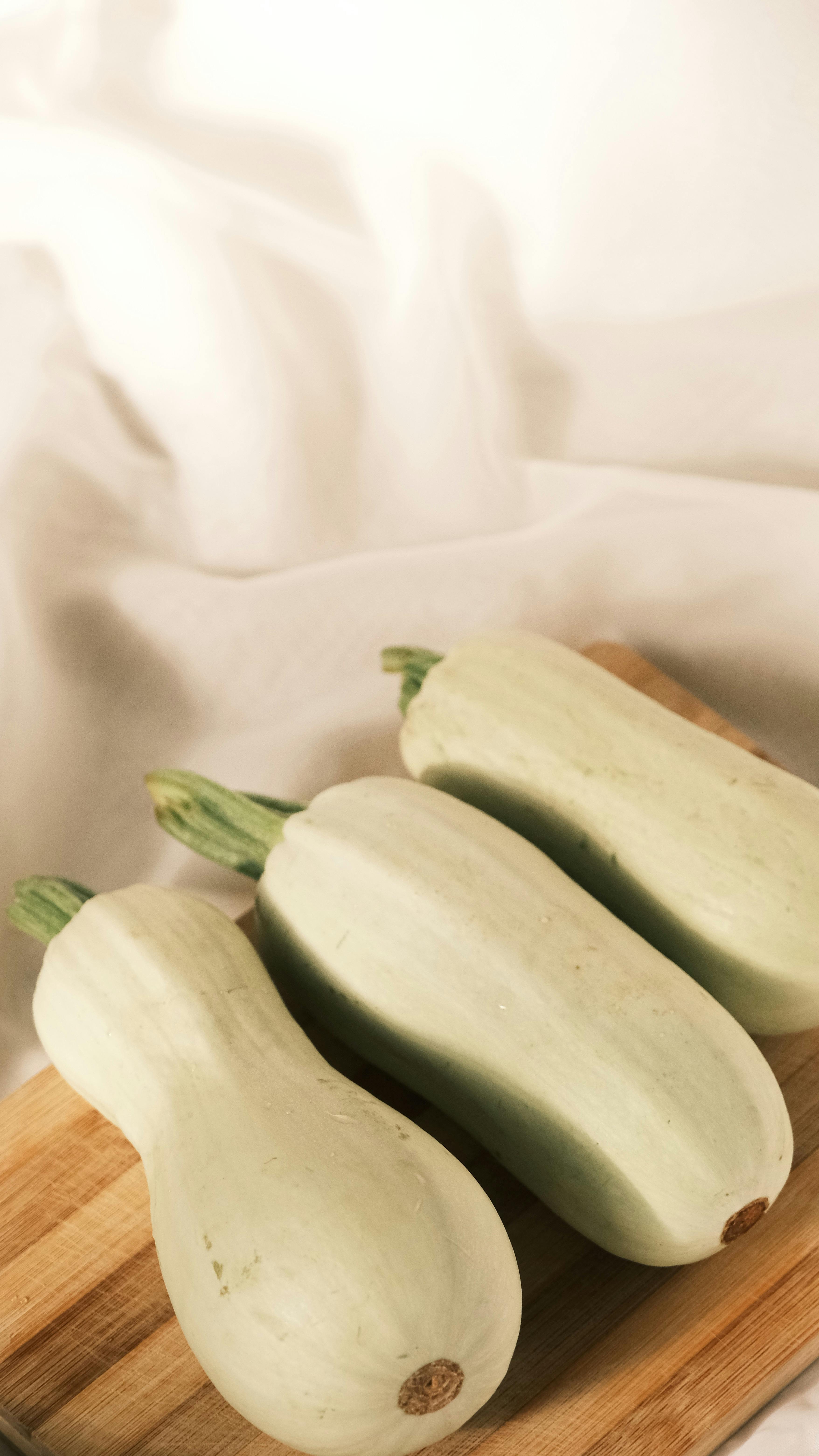 Three Light Green Squash on Cutting Board