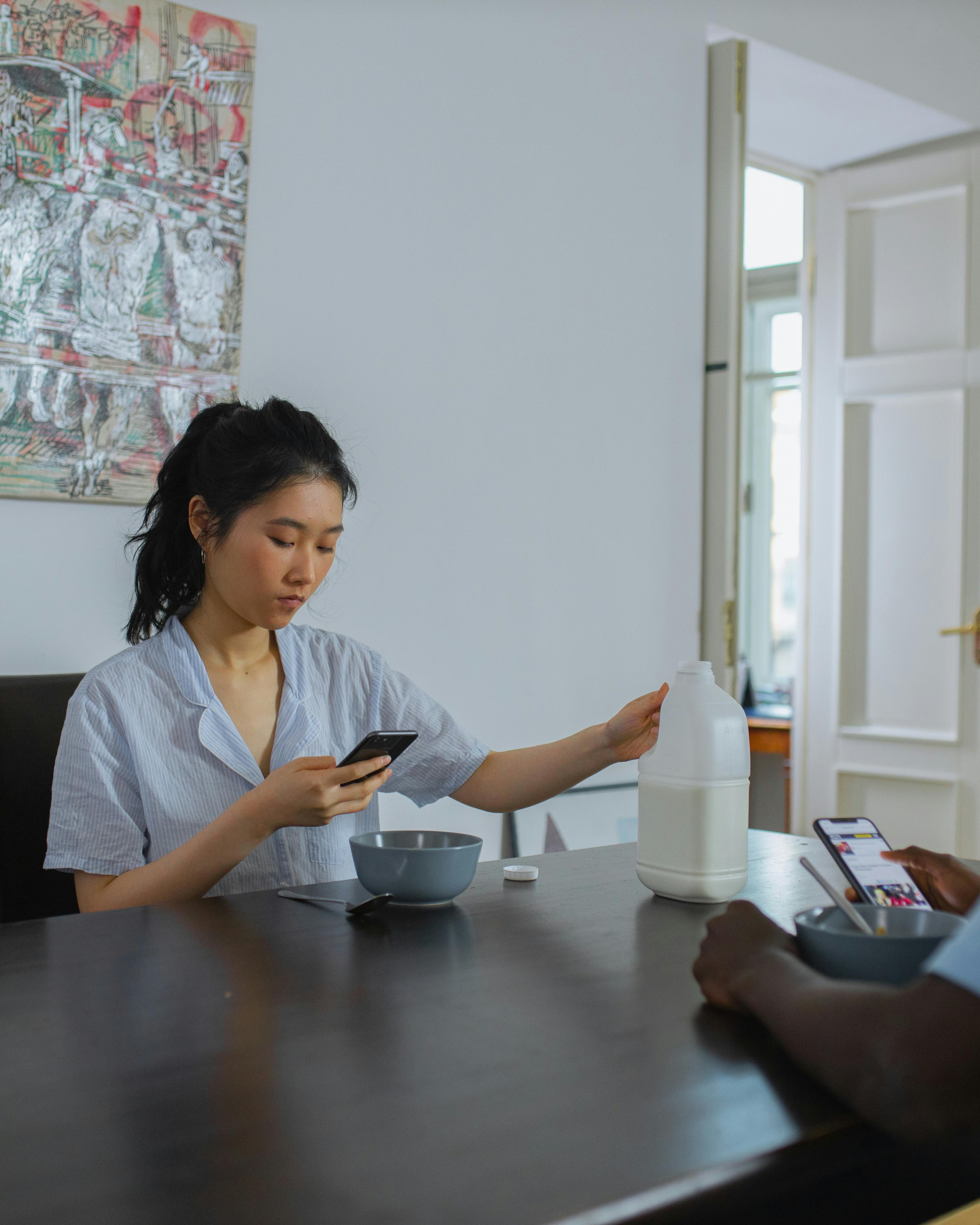 Two People Using Phones at Breakfast Table