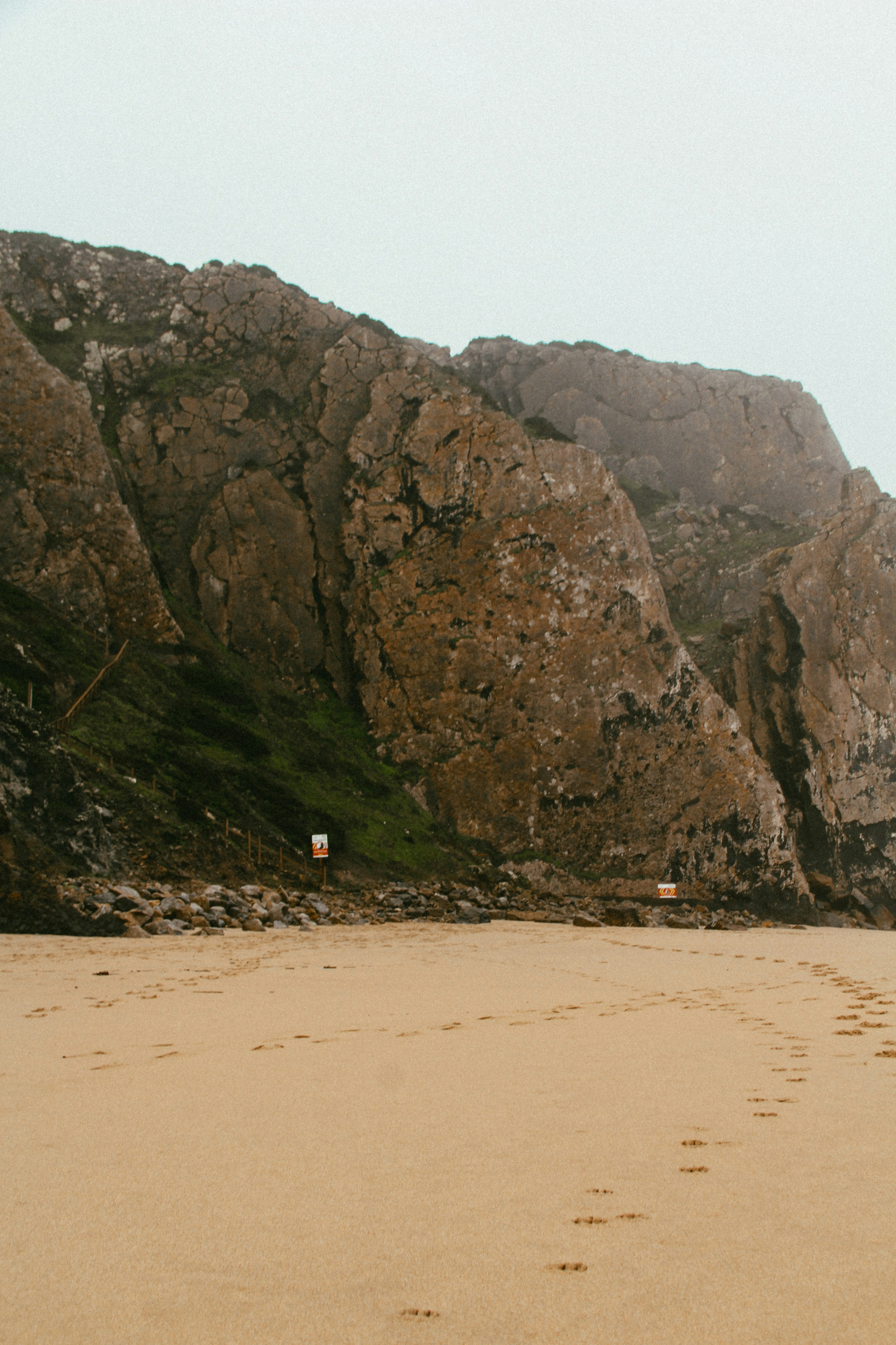 Footprints on Sandy Beach Below Cliffs