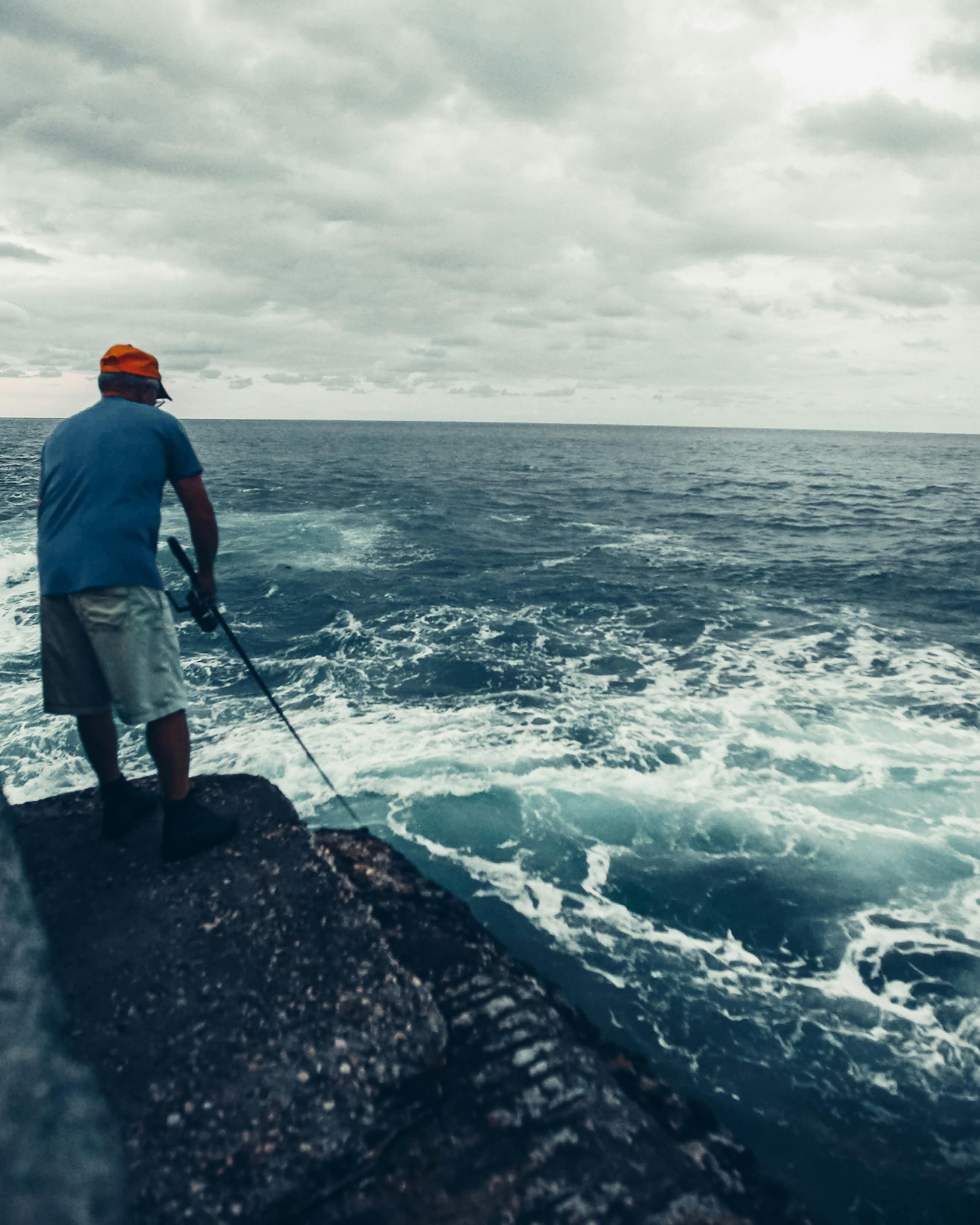 Man Fishing on Rocky Ocean Cliff
