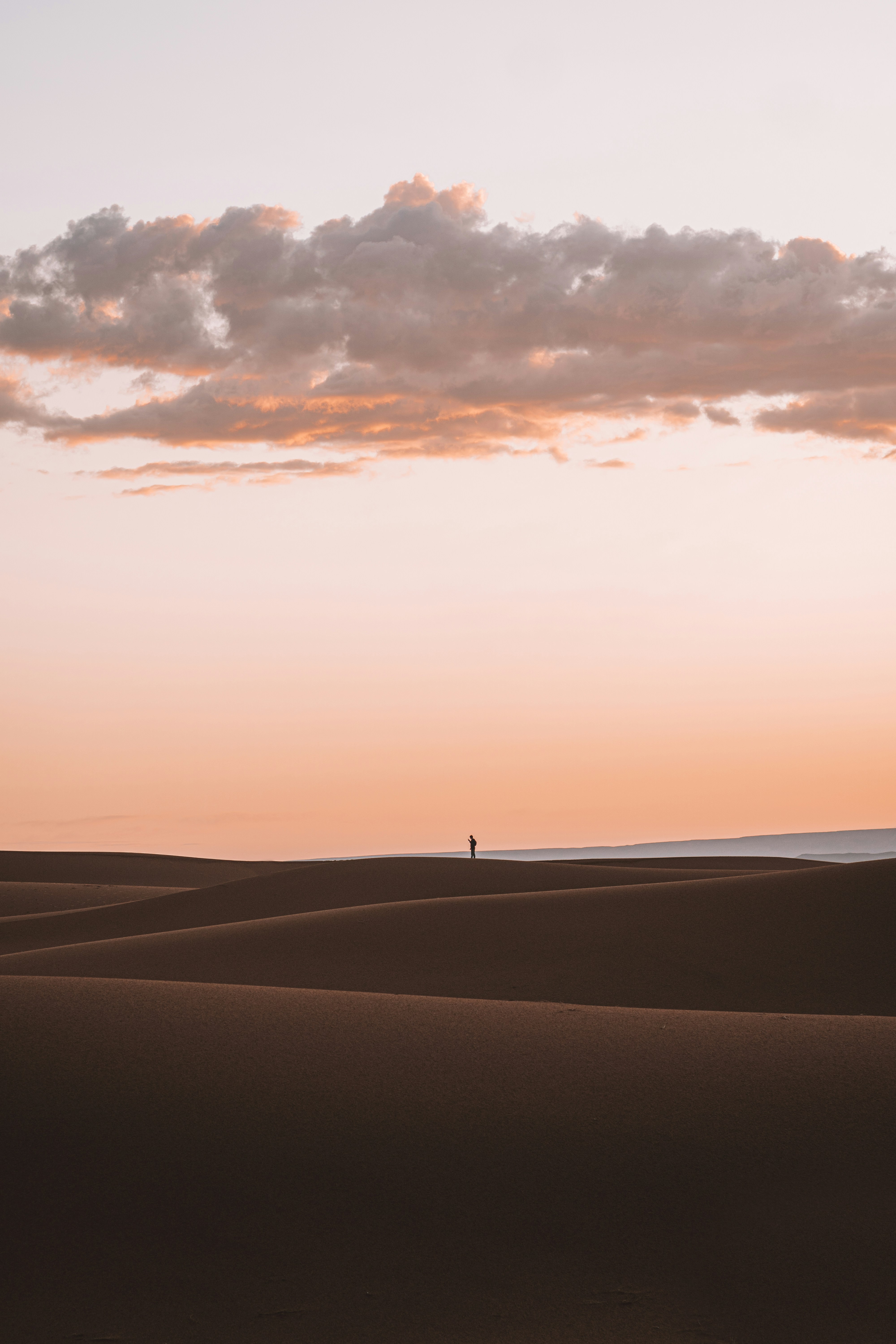Lone Figure on Desert Dunes at Sunset