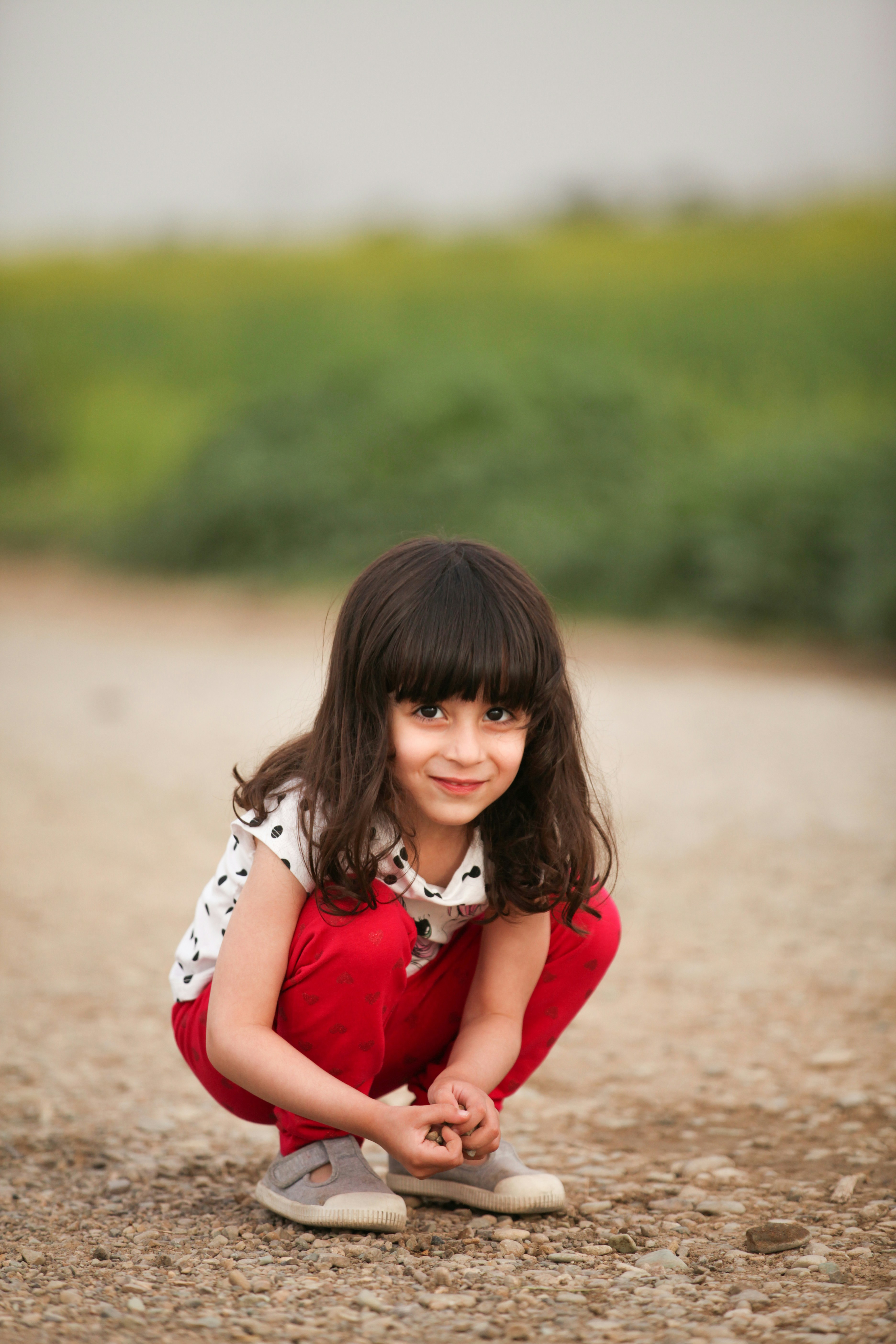 Young Girl Crouching on Gravel Path