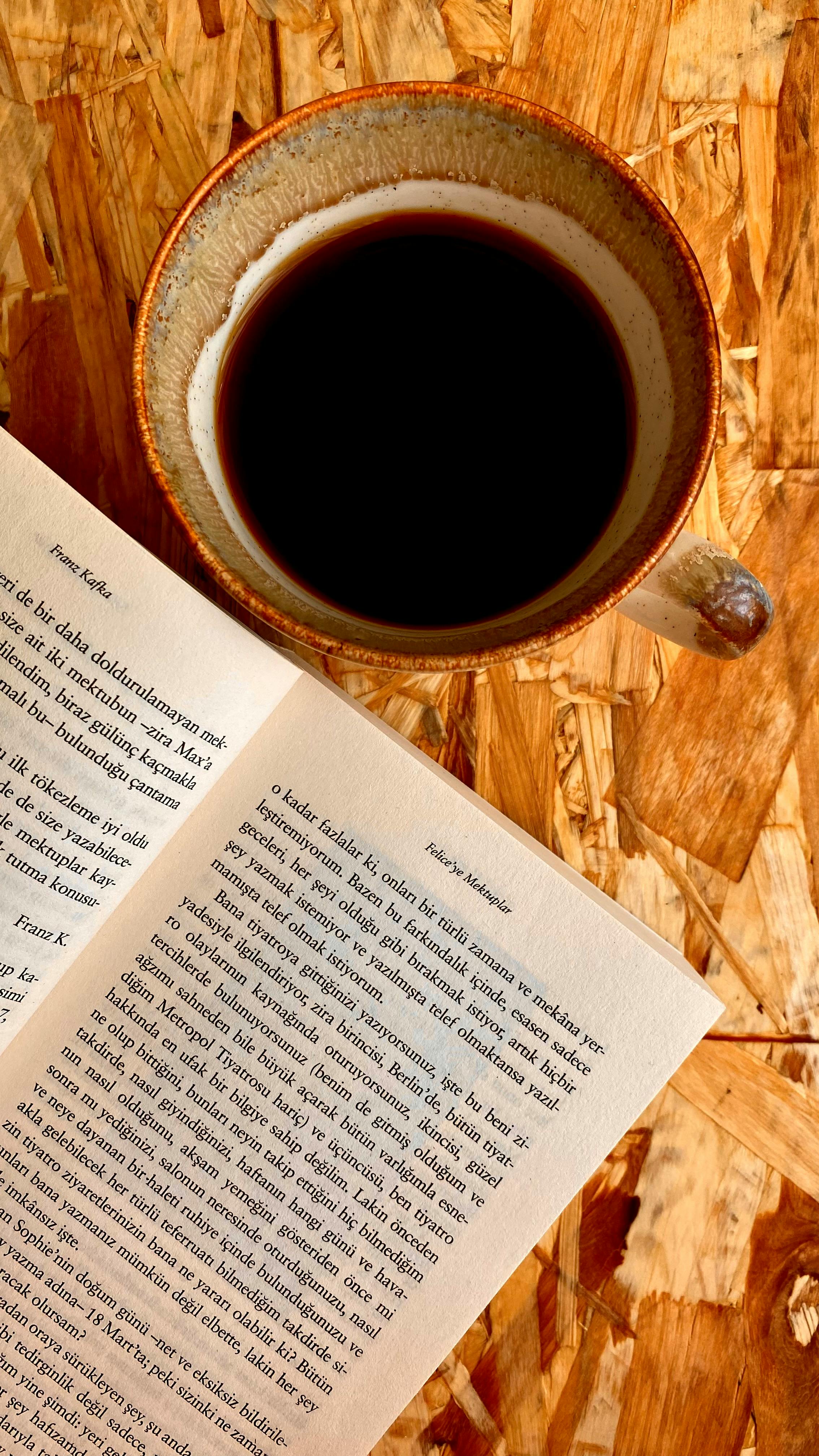 Black Coffee and Open Book on Wooden Table