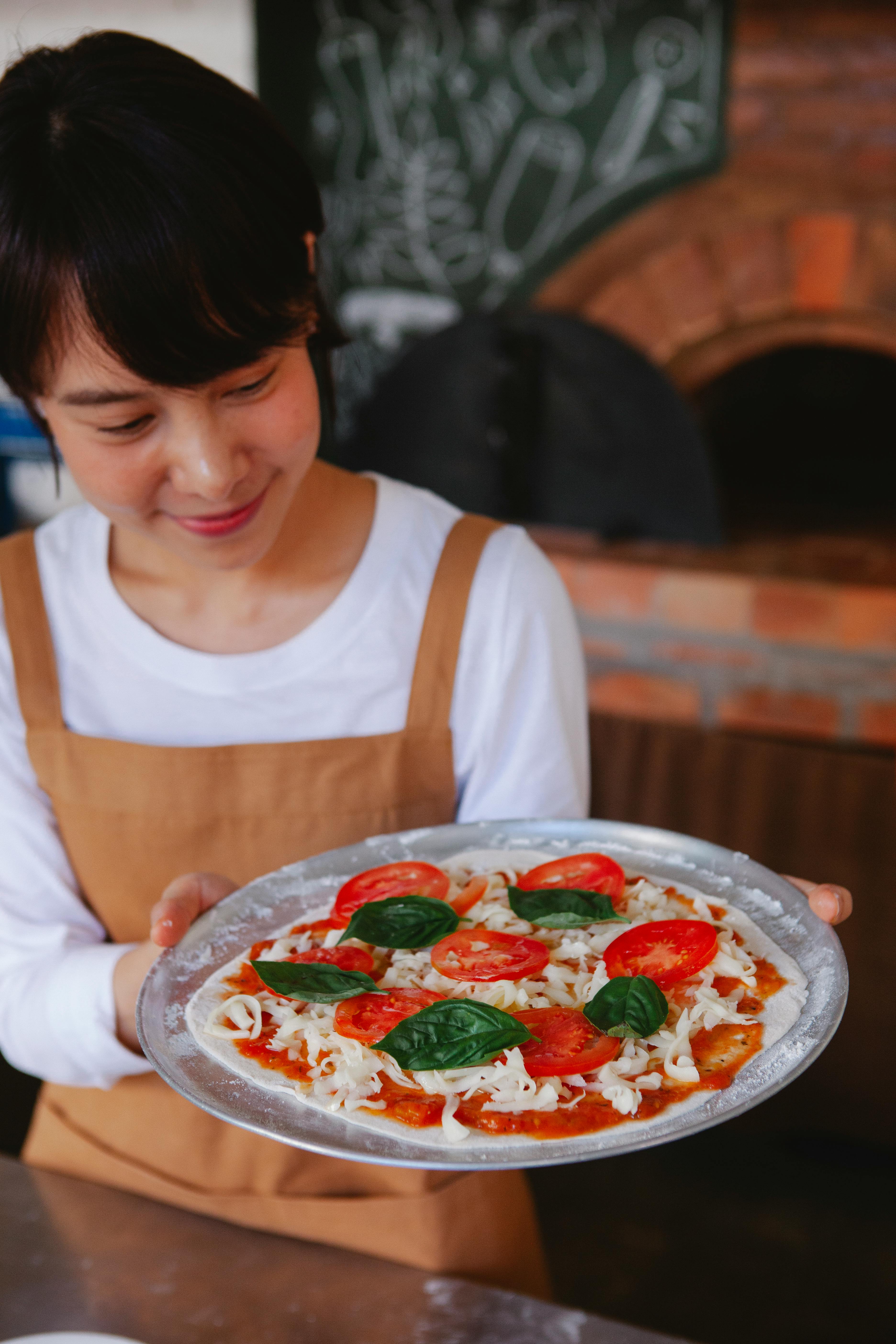Woman holding uncooked homemade pizza
