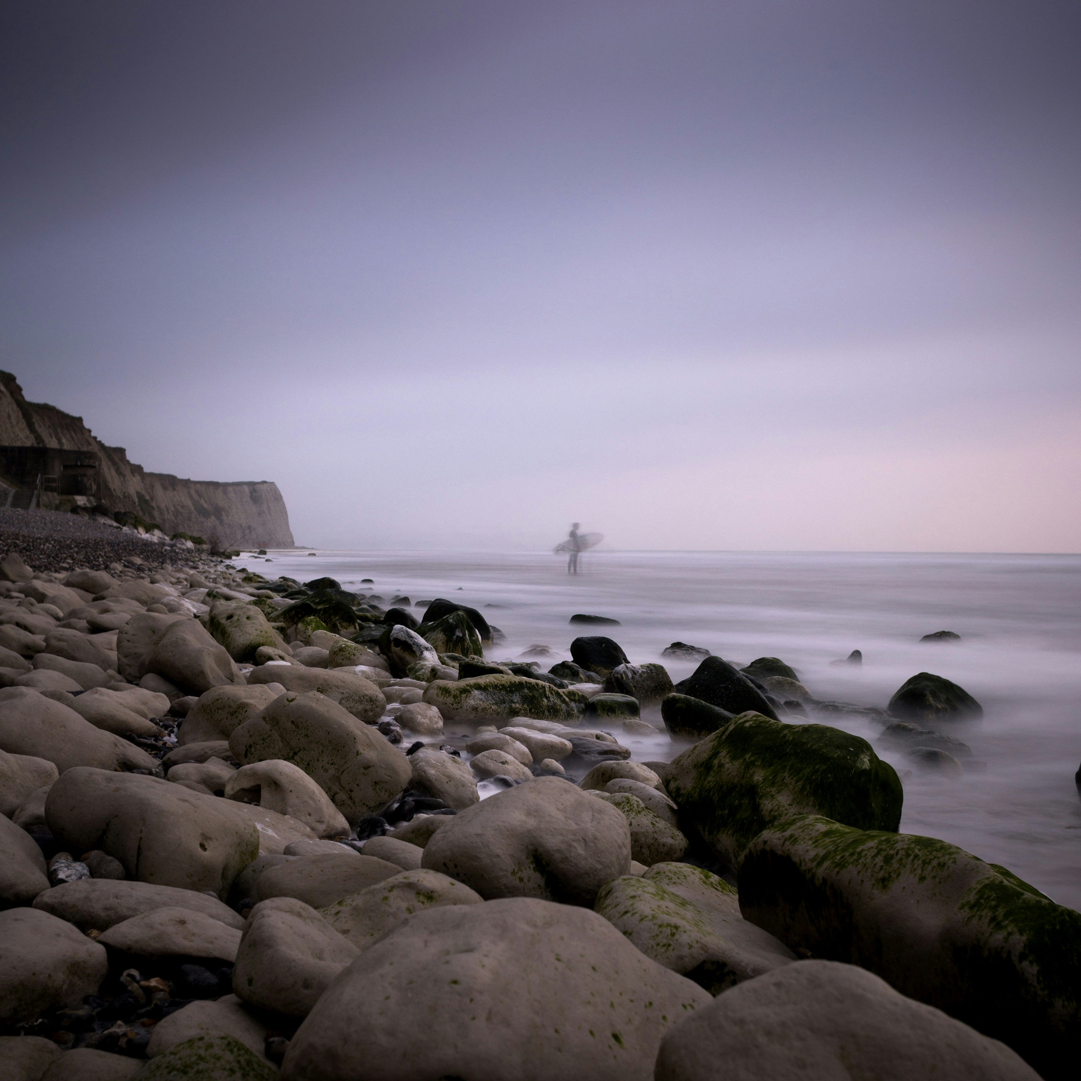 Surfer on Pebble Beach at Dusk