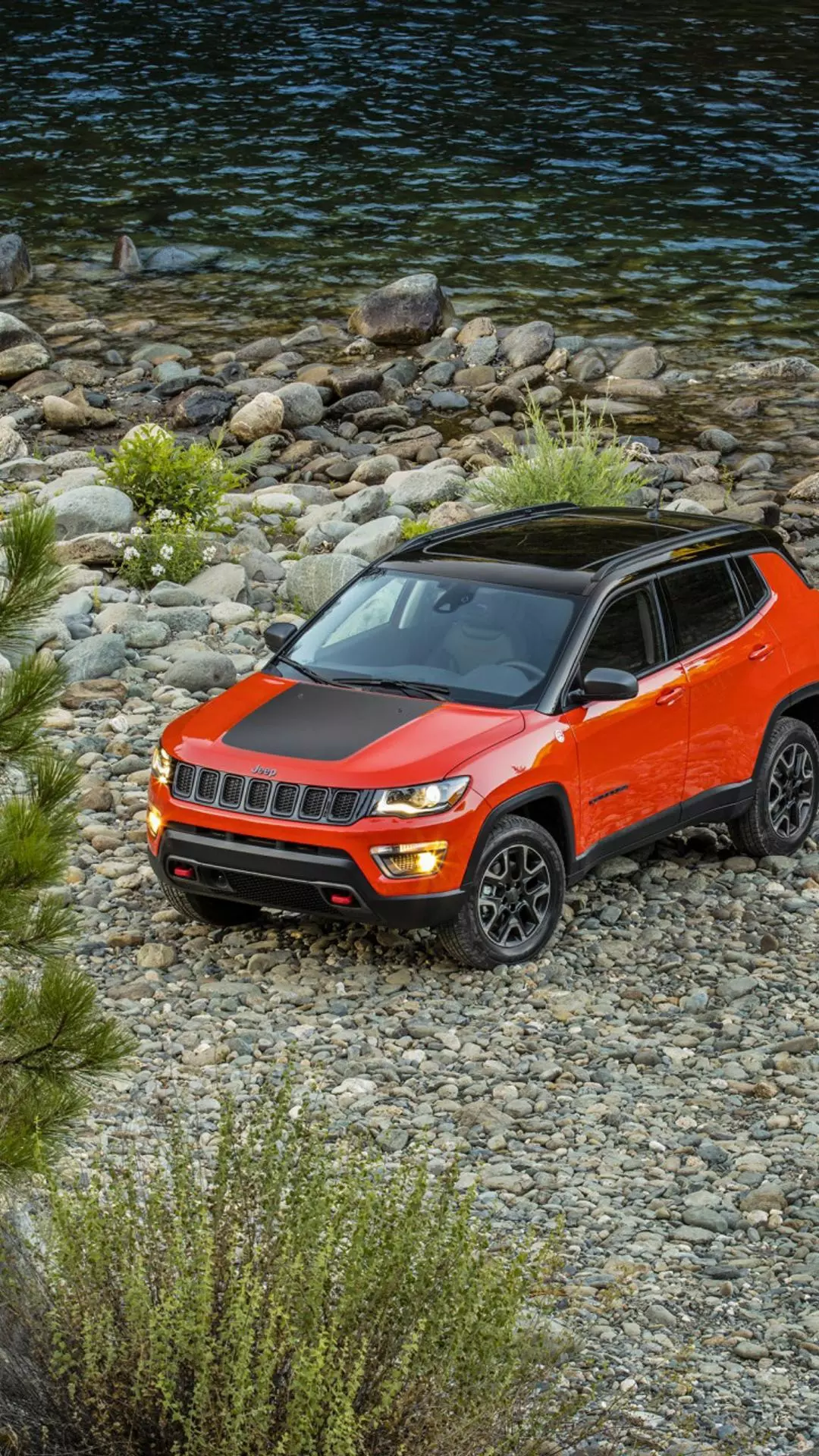 Orange Jeep on Rocky Riverbank