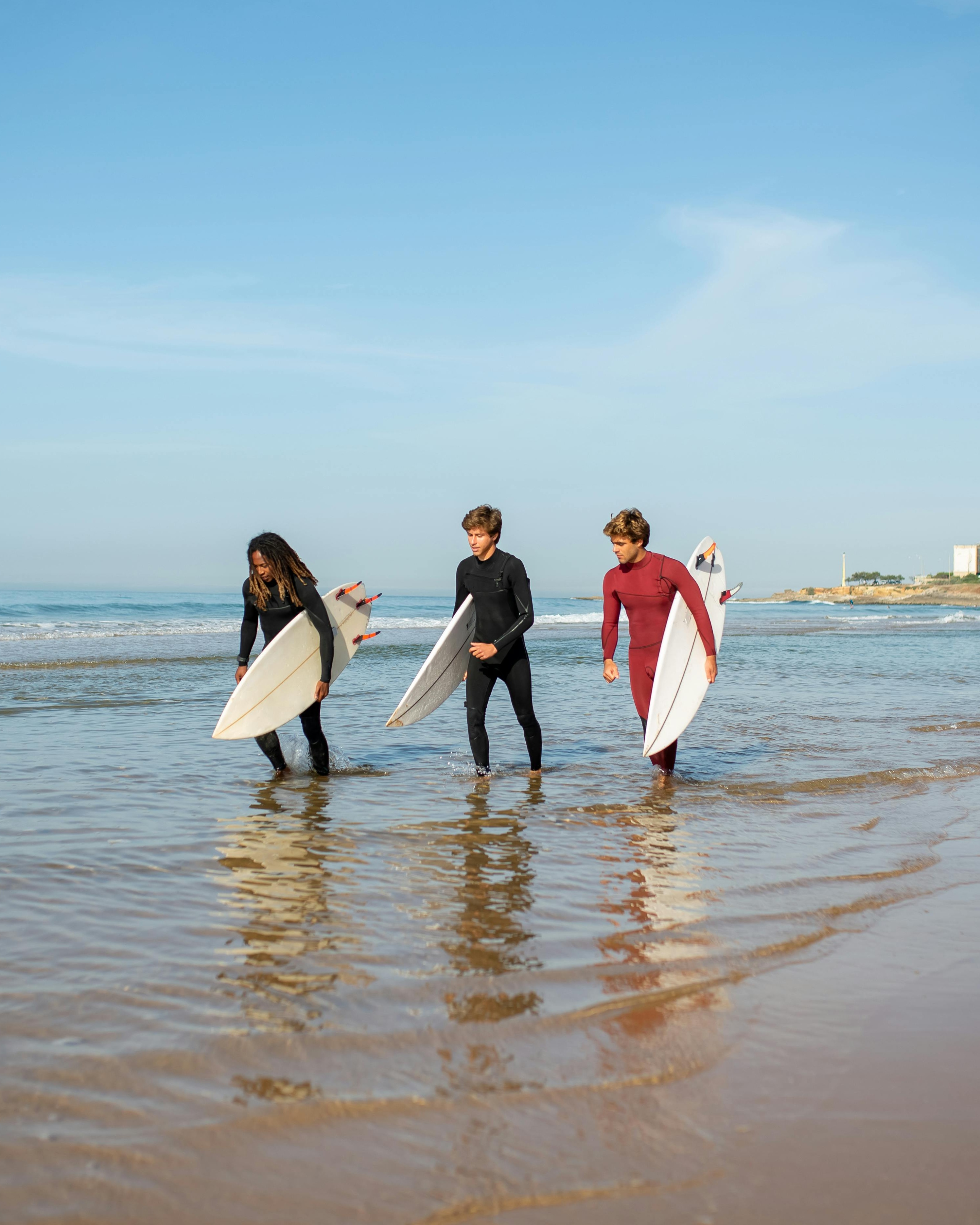 Three Surfers Walking in Shallow Sea