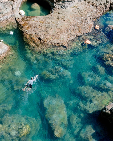 Swimmer in Clear Rocky Coastal Water