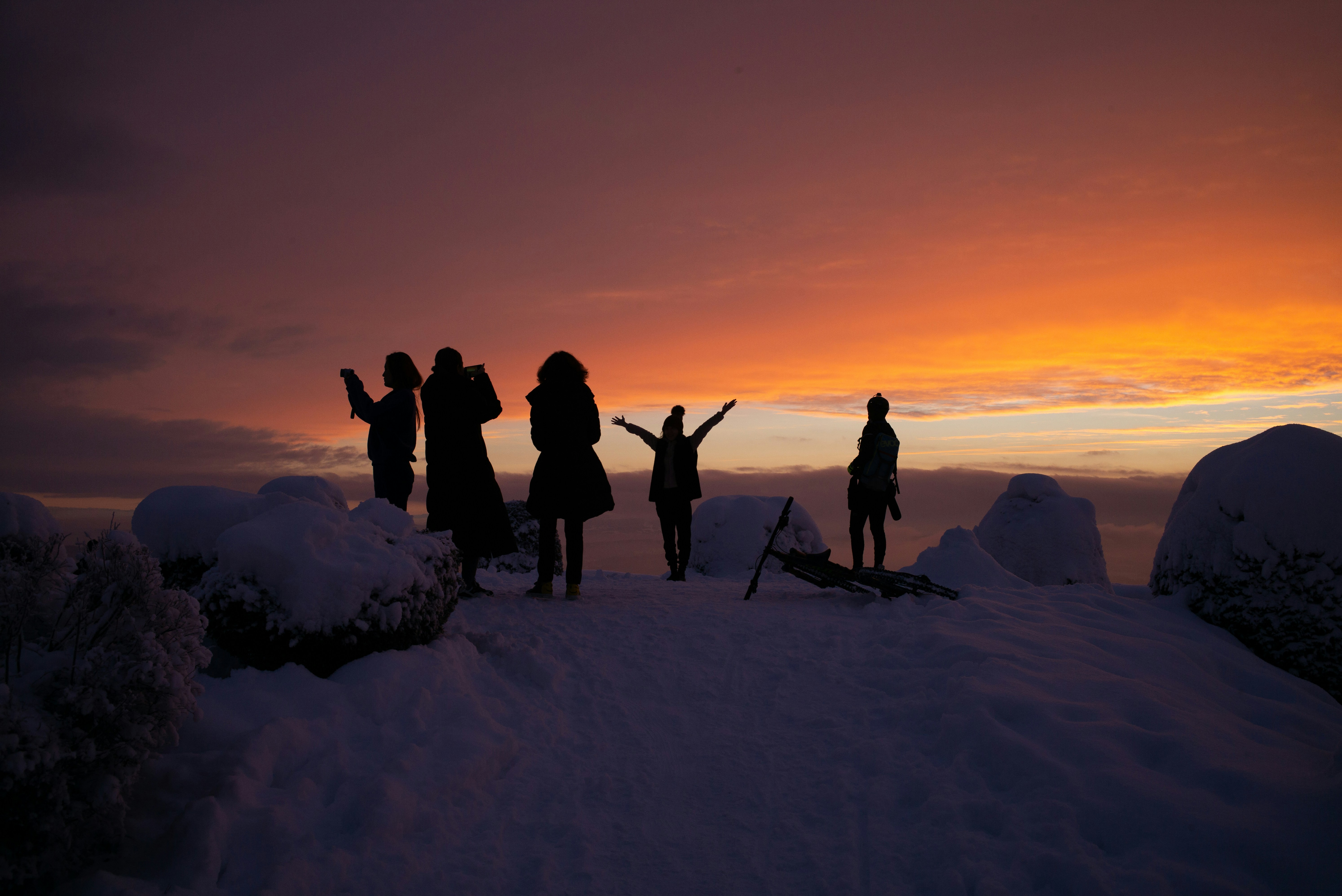 Silhouetted Hikers Enjoying Sunset on Snowy Peak