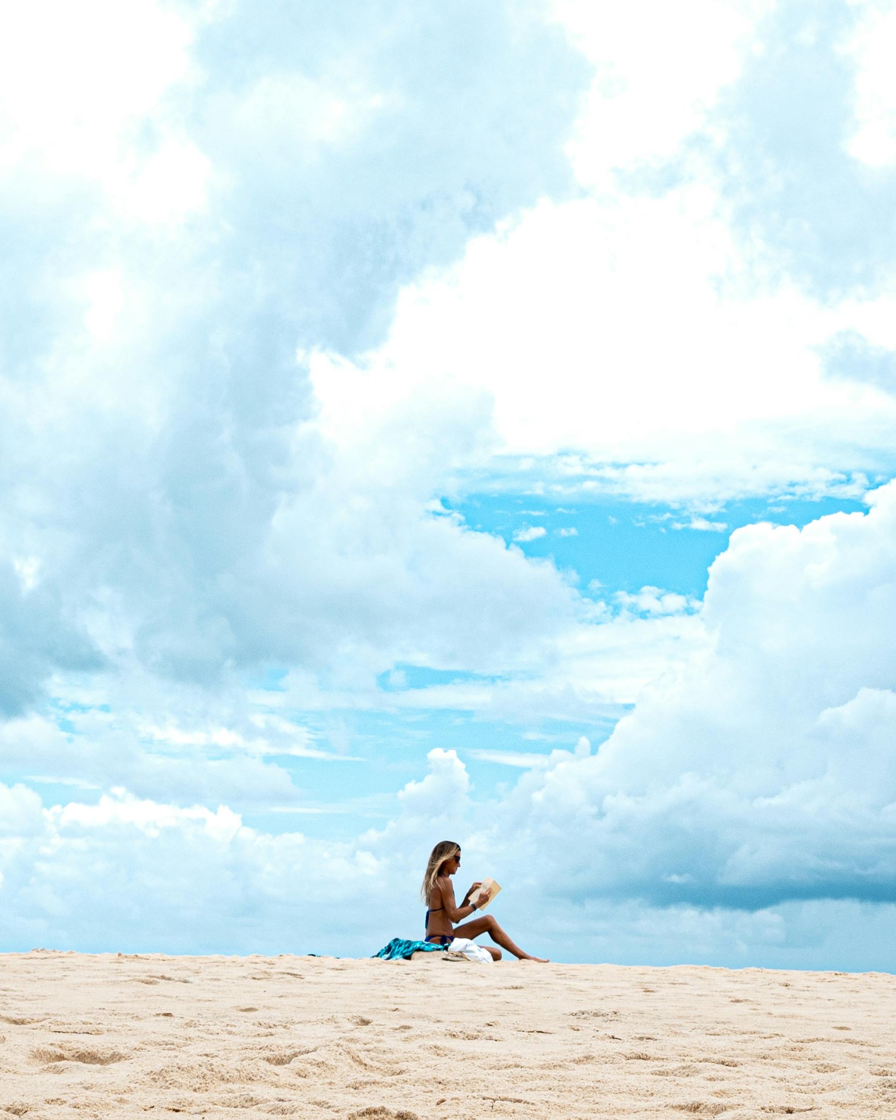 Woman Reading on Sandy Beach