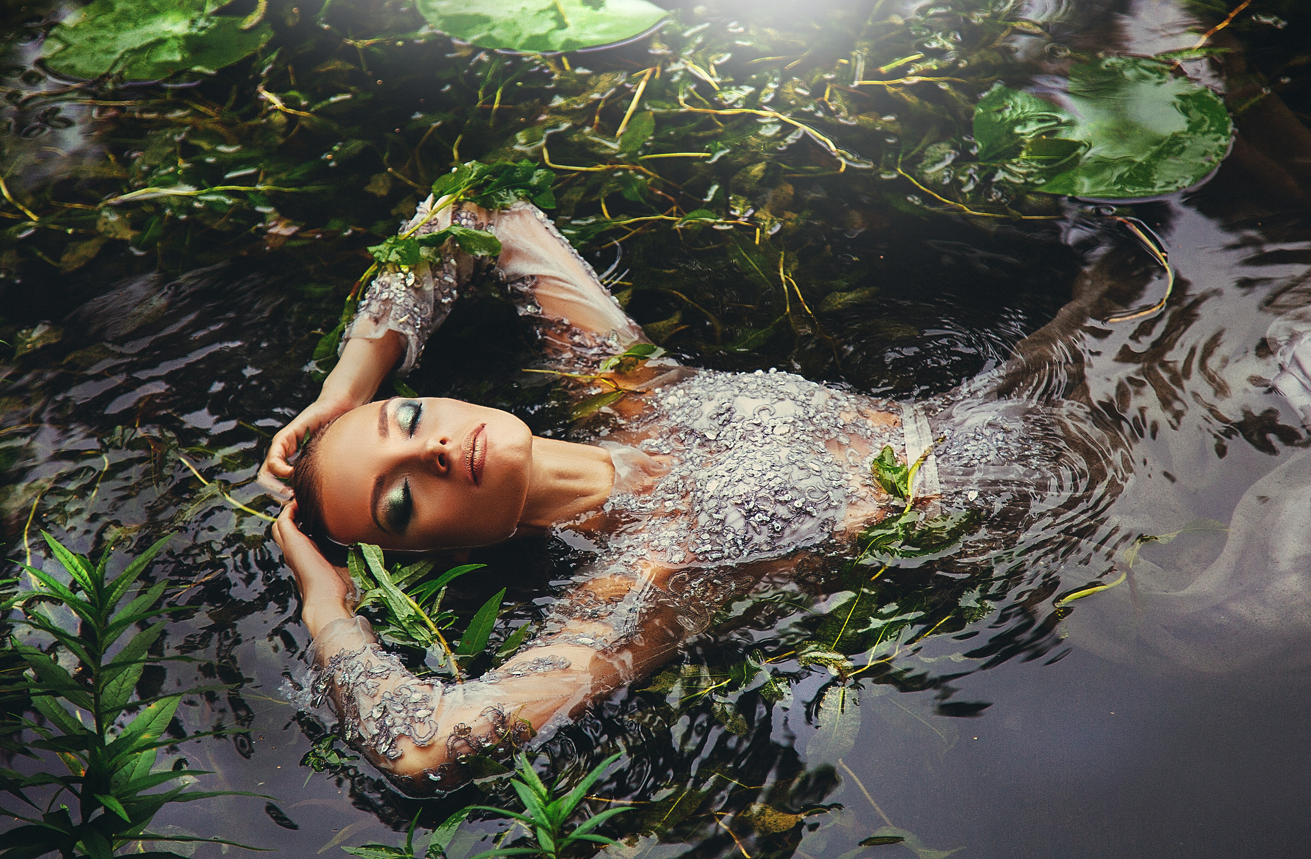 Woman Reclining in Pond Water Among Lilies
