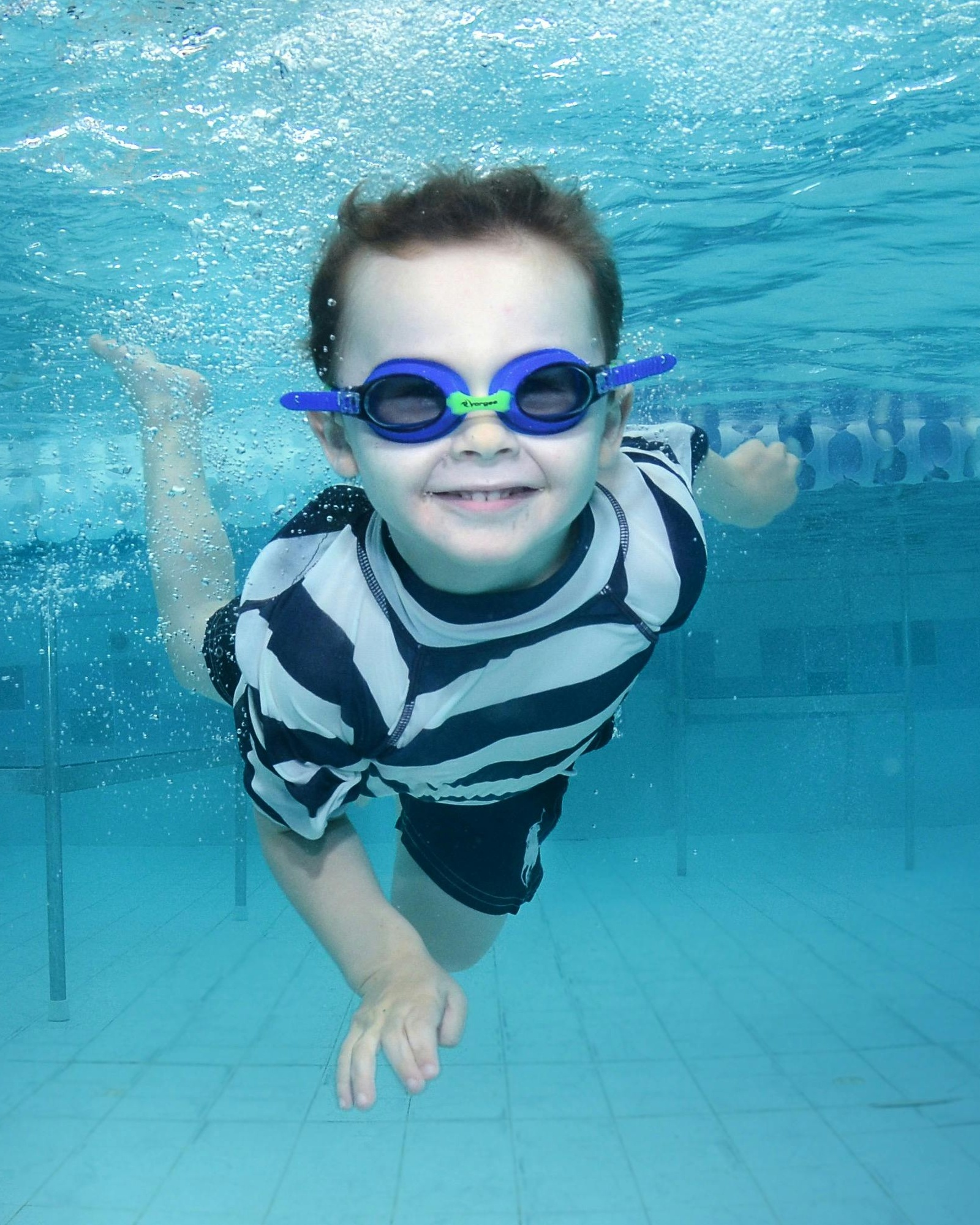 Smiling Boy Swimming Underwater in Pool