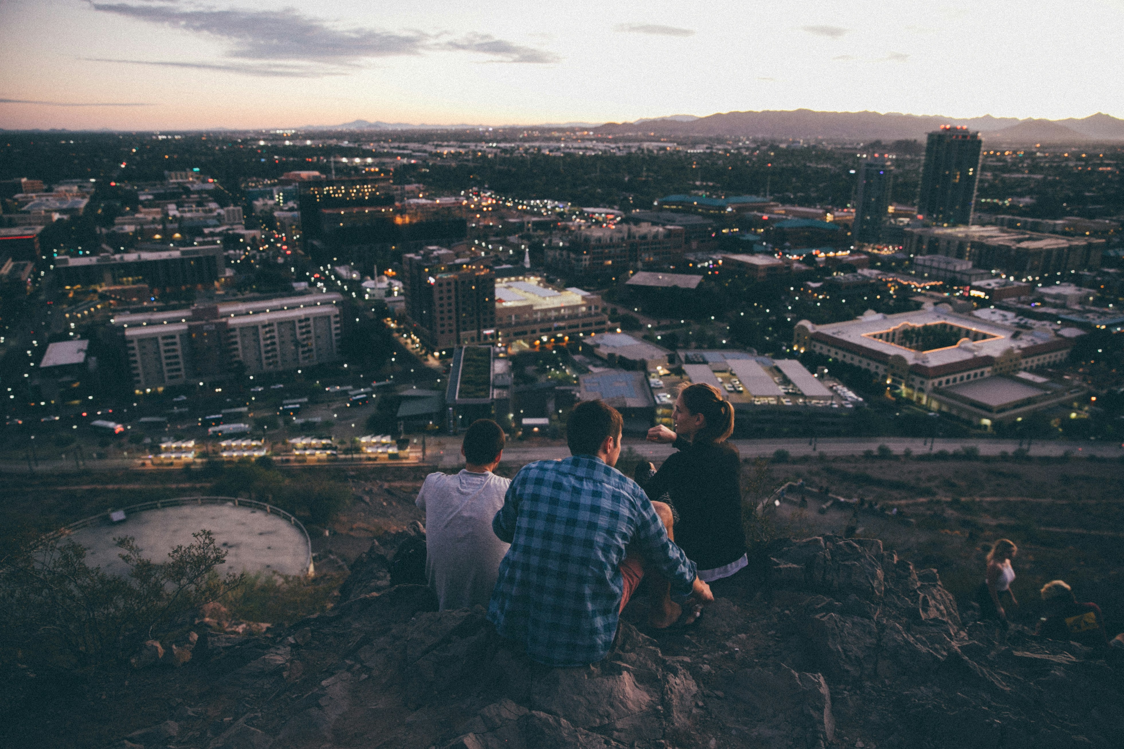 Three People Overlook City at Dusk
