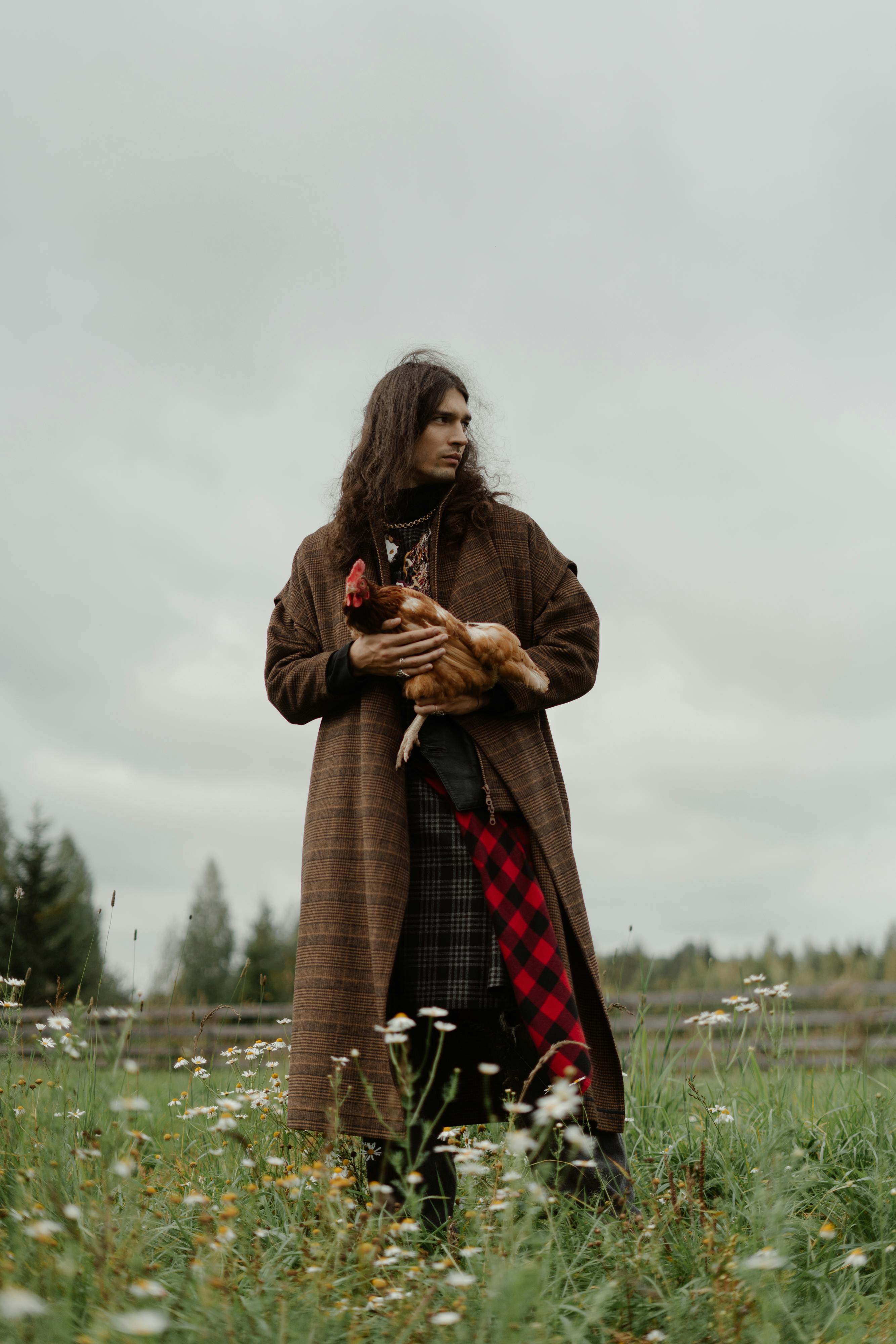 Man Holding Chicken In Wild Meadow