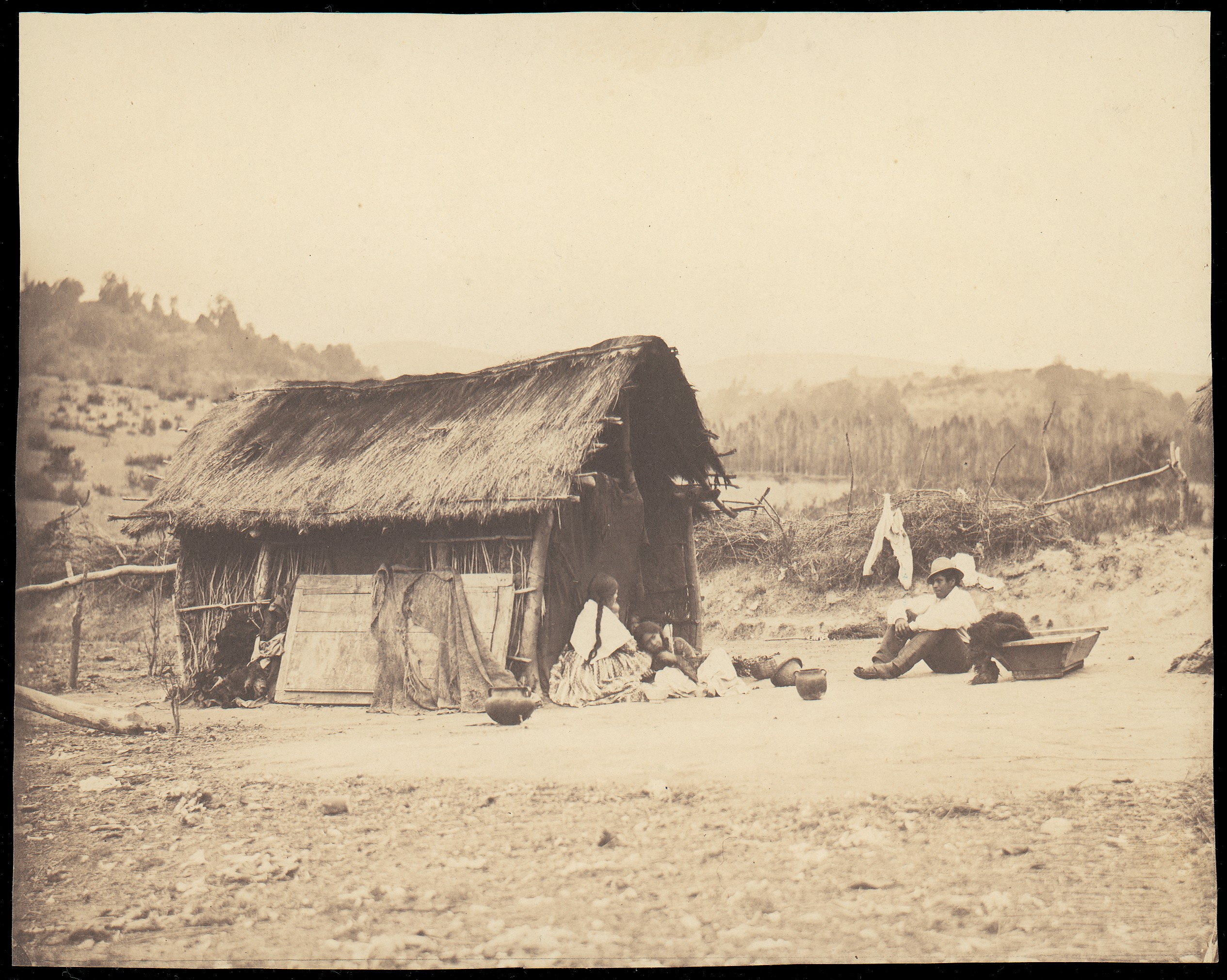 People Resting Outside Thatched Hut