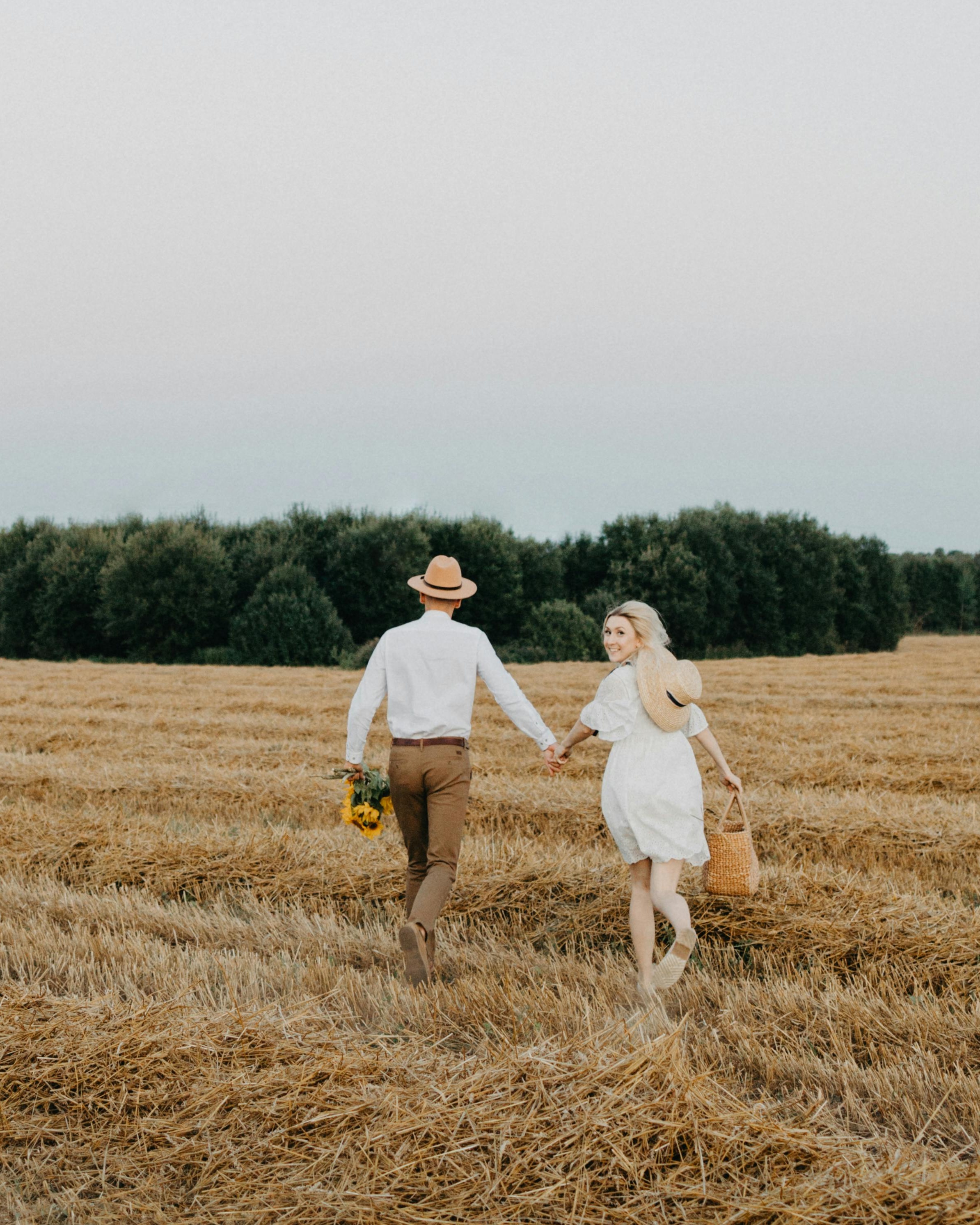 Couple Holding Hands Walking in Hay Field