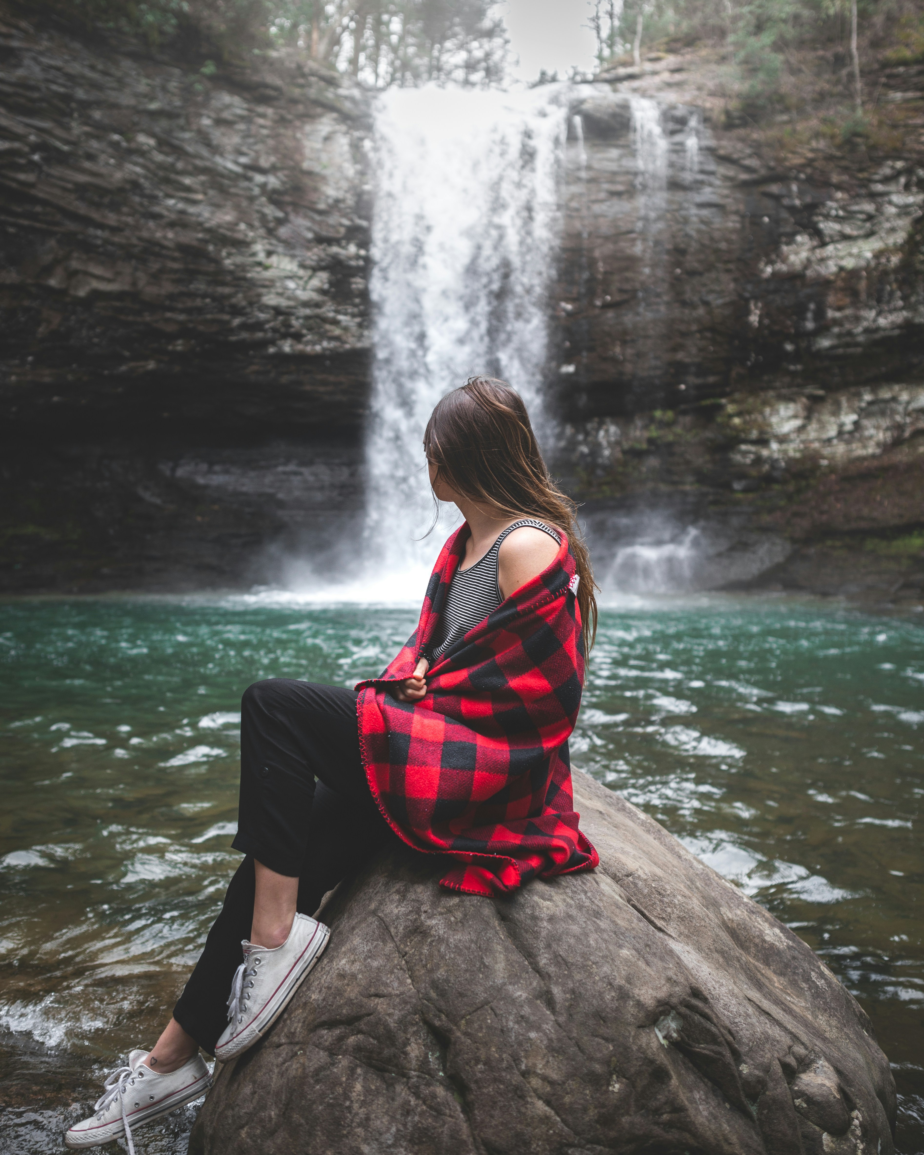 Woman Sitting By Forest Waterfall