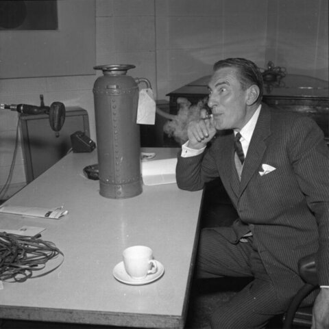 Suited Man Smoking Beside Coffee Urn In Studio