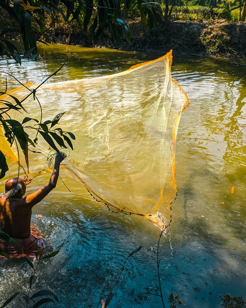 Fisherman Casting Net in River