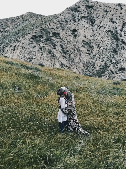 Two People Embracing on Mountain Grassland