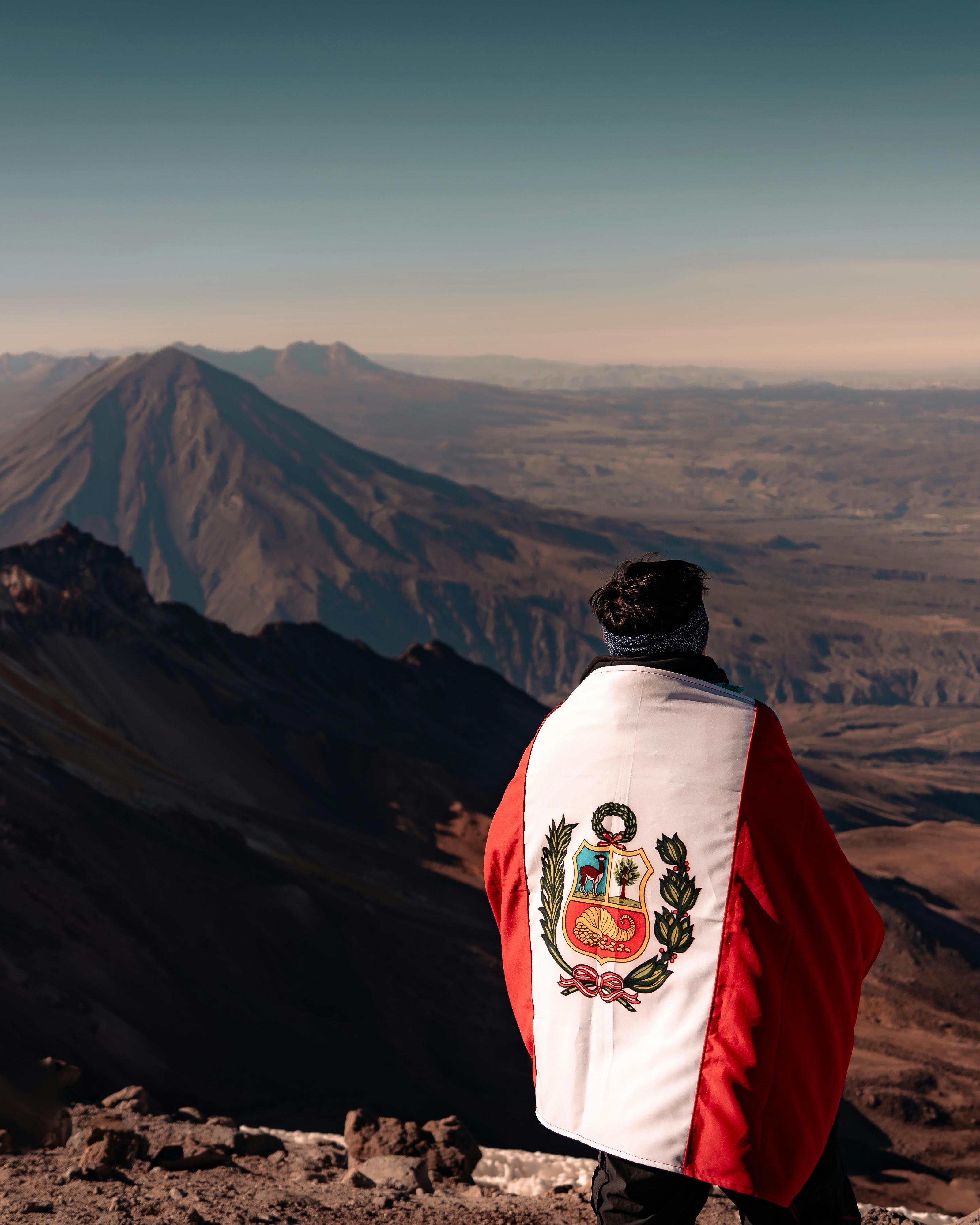 Climber with Peruvian Flag on Mountain Peak