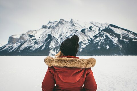 Woman Facing Snow Mountains On Frozen Lake