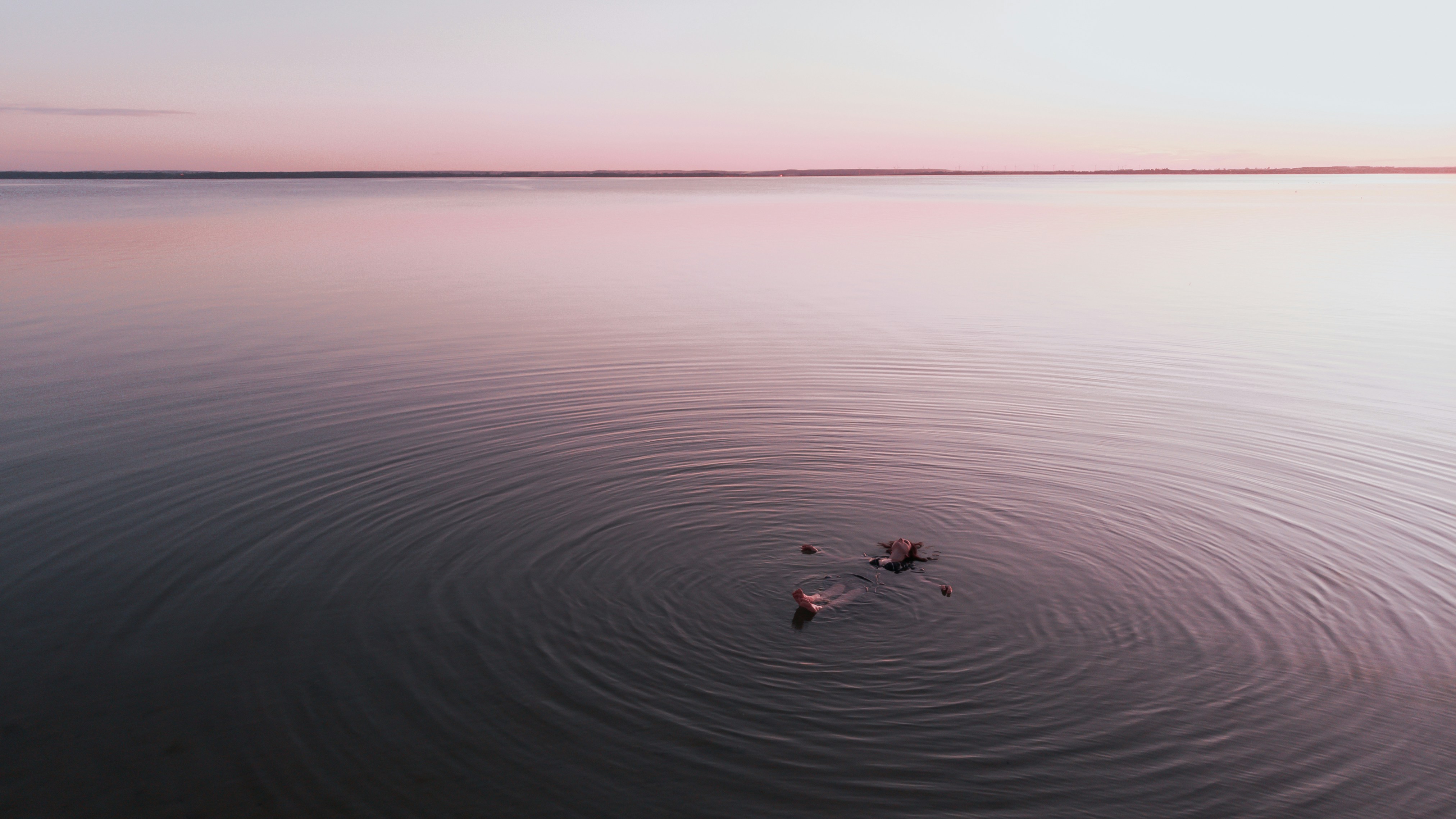 Person Floating In Pink Dusk Lake