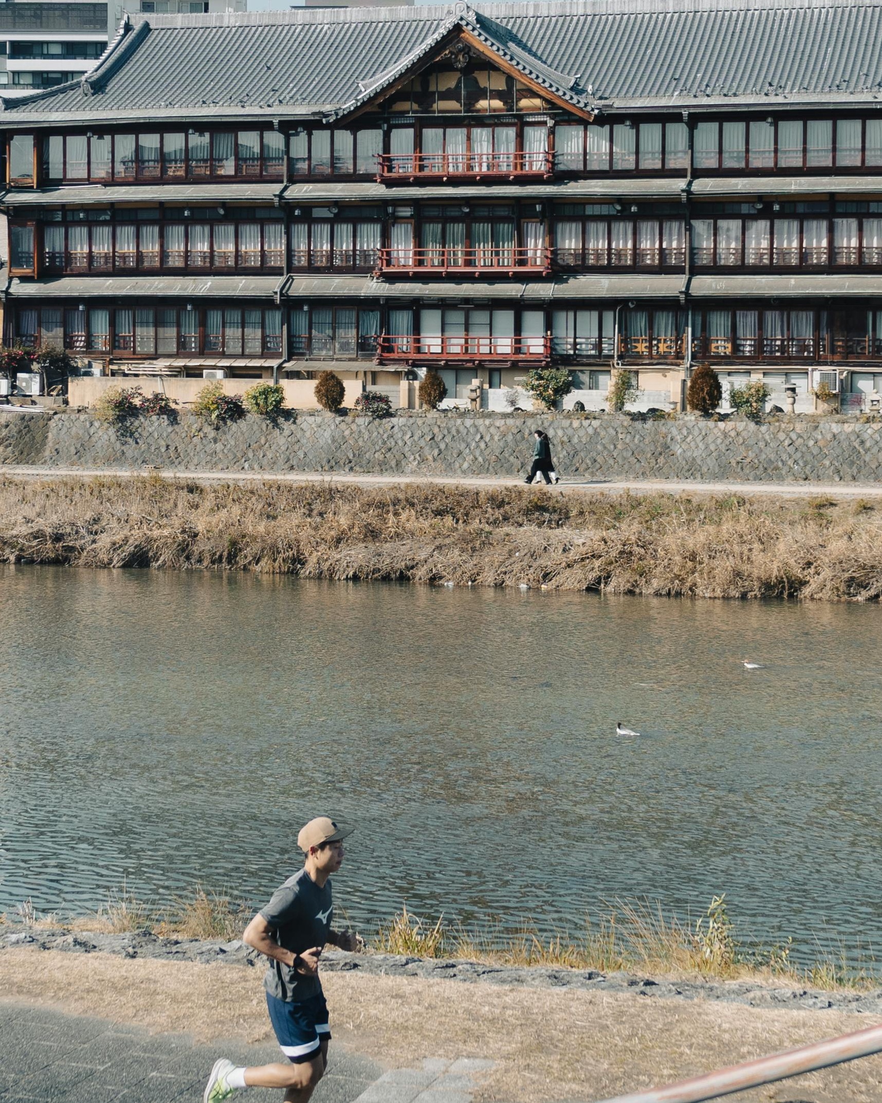 Jogging by River with Traditional Japanese Building
