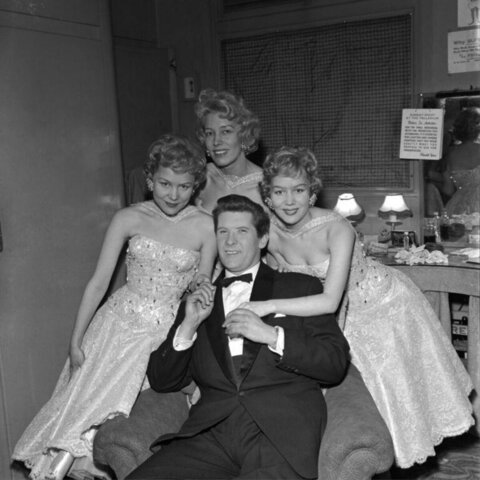 Man with three performers in backstage dressing room
