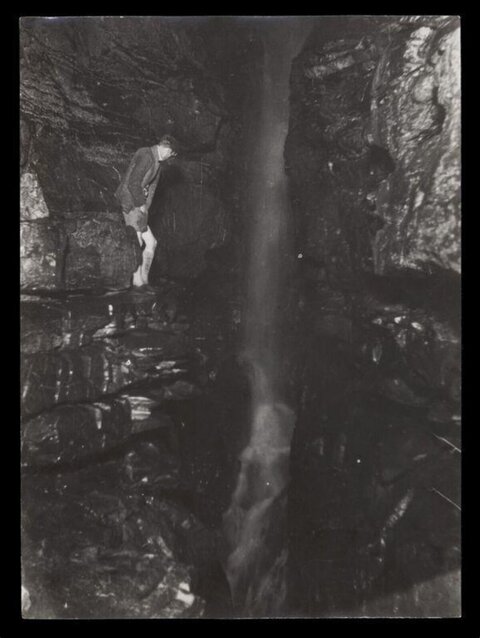 Man Observing Underground Cave Waterfall