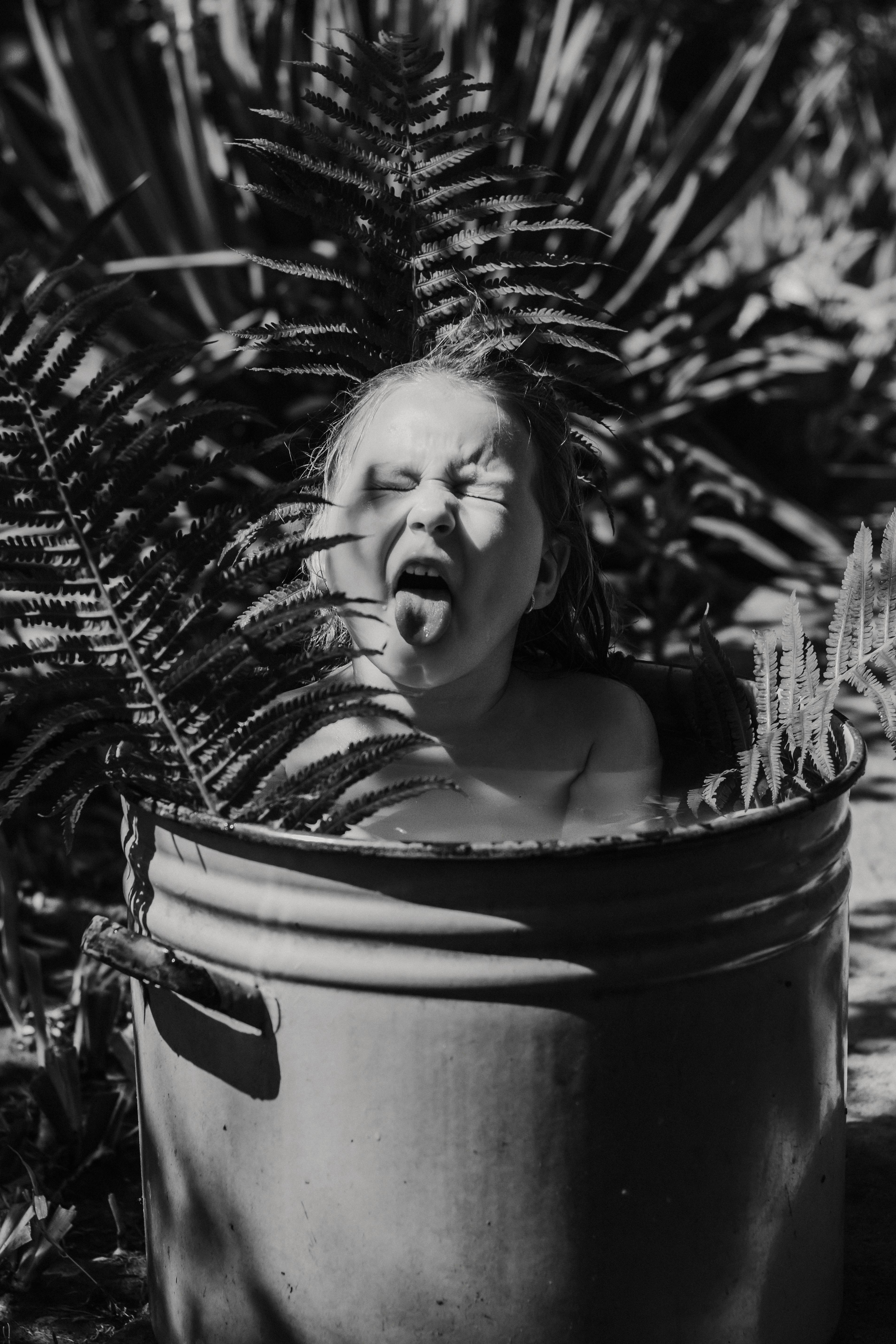 Little Girl Bathing in Bucket Among Ferns