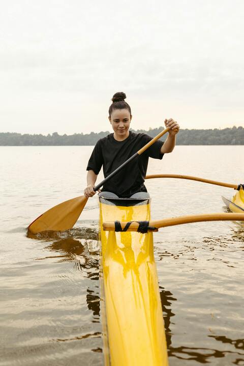 Woman Paddling Outrigger Canoe on Lake