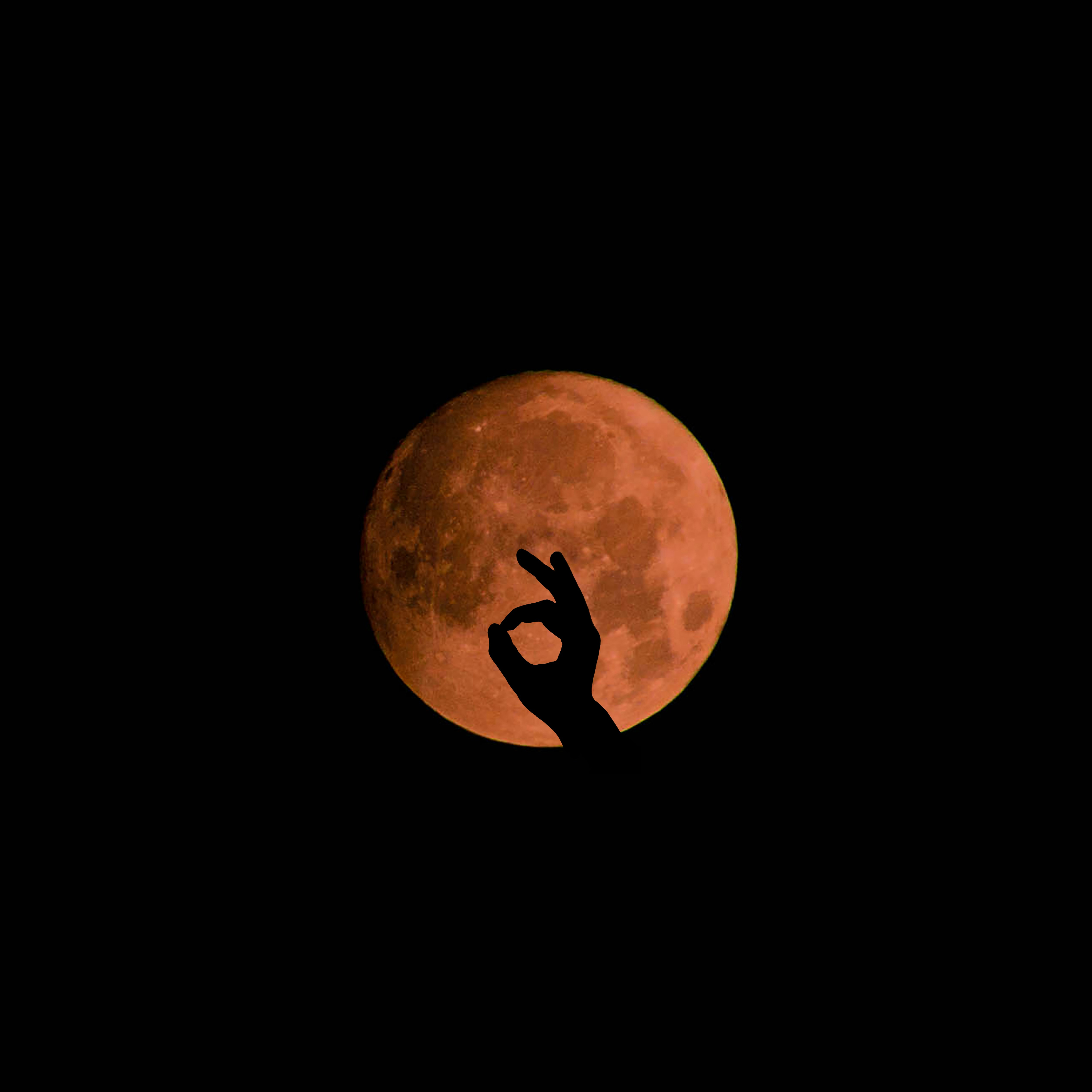 OK Hand Silhouette Against Red Full Moon